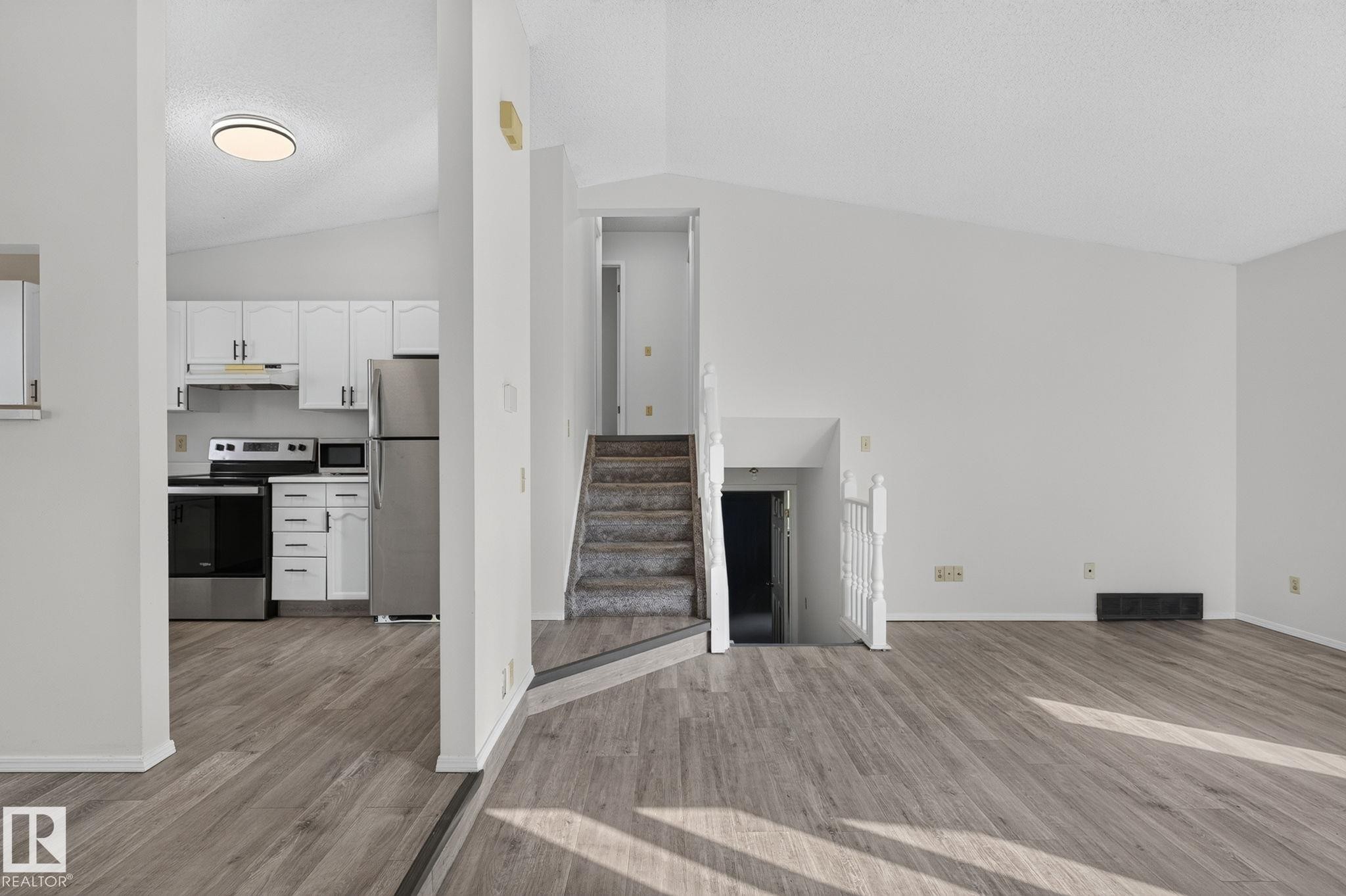 Spacious living area featuring wood-finish flooring and a vaulted ceiling - 3722 34A Avenue Nw, Edmonton, AB - Indoor