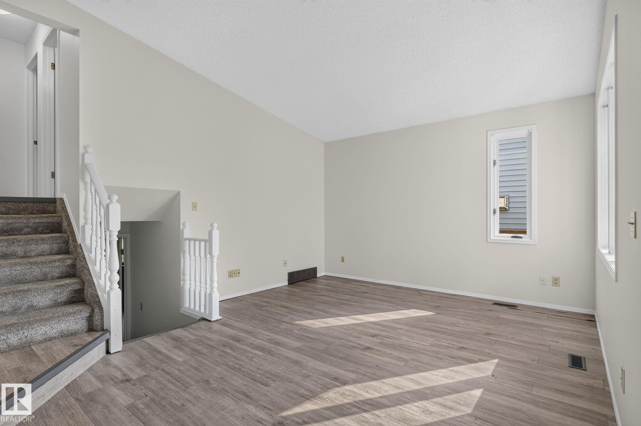 Spacious room featuring wood-finish flooring, light-toned walls, and a window providing natural illumination - 3722 34A Avenue Nw, Edmonton, AB - Indoor Photo Showing Other Room