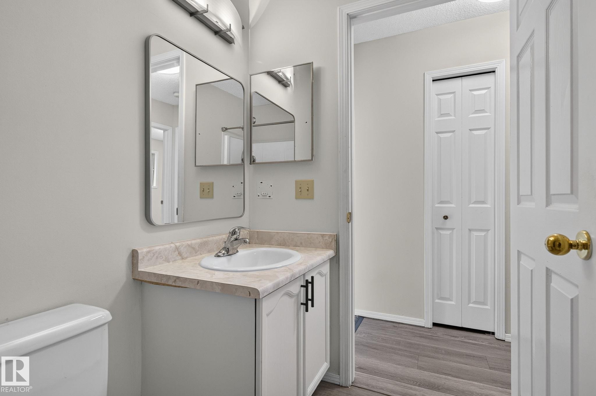Bathroom vanity featuring a white cabinet with black hardware, a light-toned countertop, and an integrated sink - 3722 34A Avenue Nw, Edmonton, AB - Indoor Photo Showing Bathroom