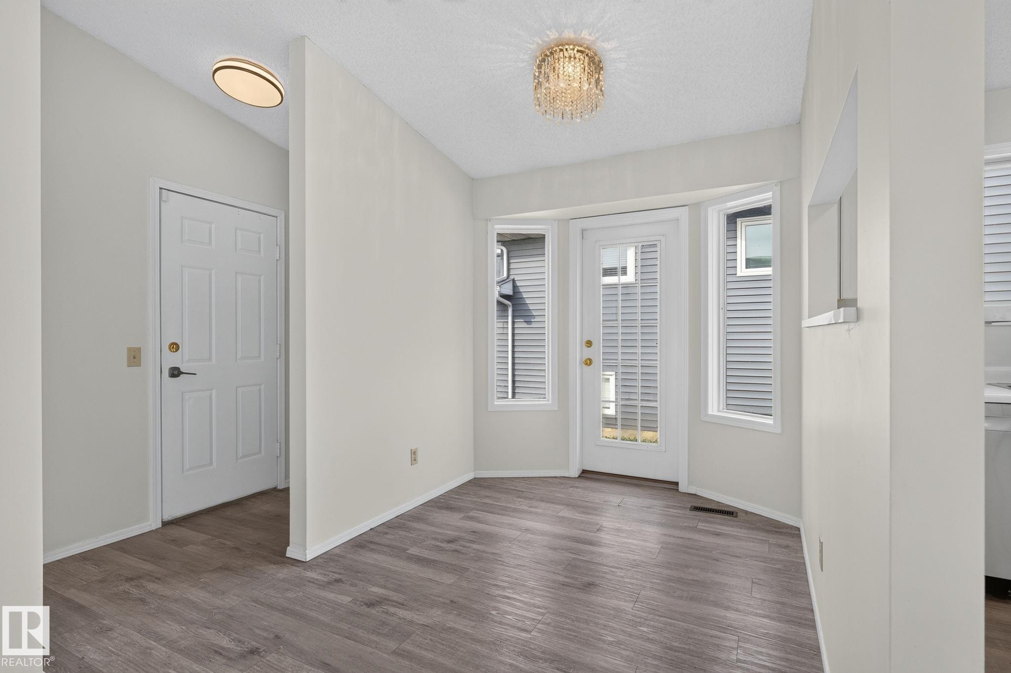 Dining area featuring wood-finish flooring, a crystal chandelier, and a bay window with a glass-paned door - 3722 34A Avenue Nw, Edmonton, AB - Indoor Photo Showing Other Room