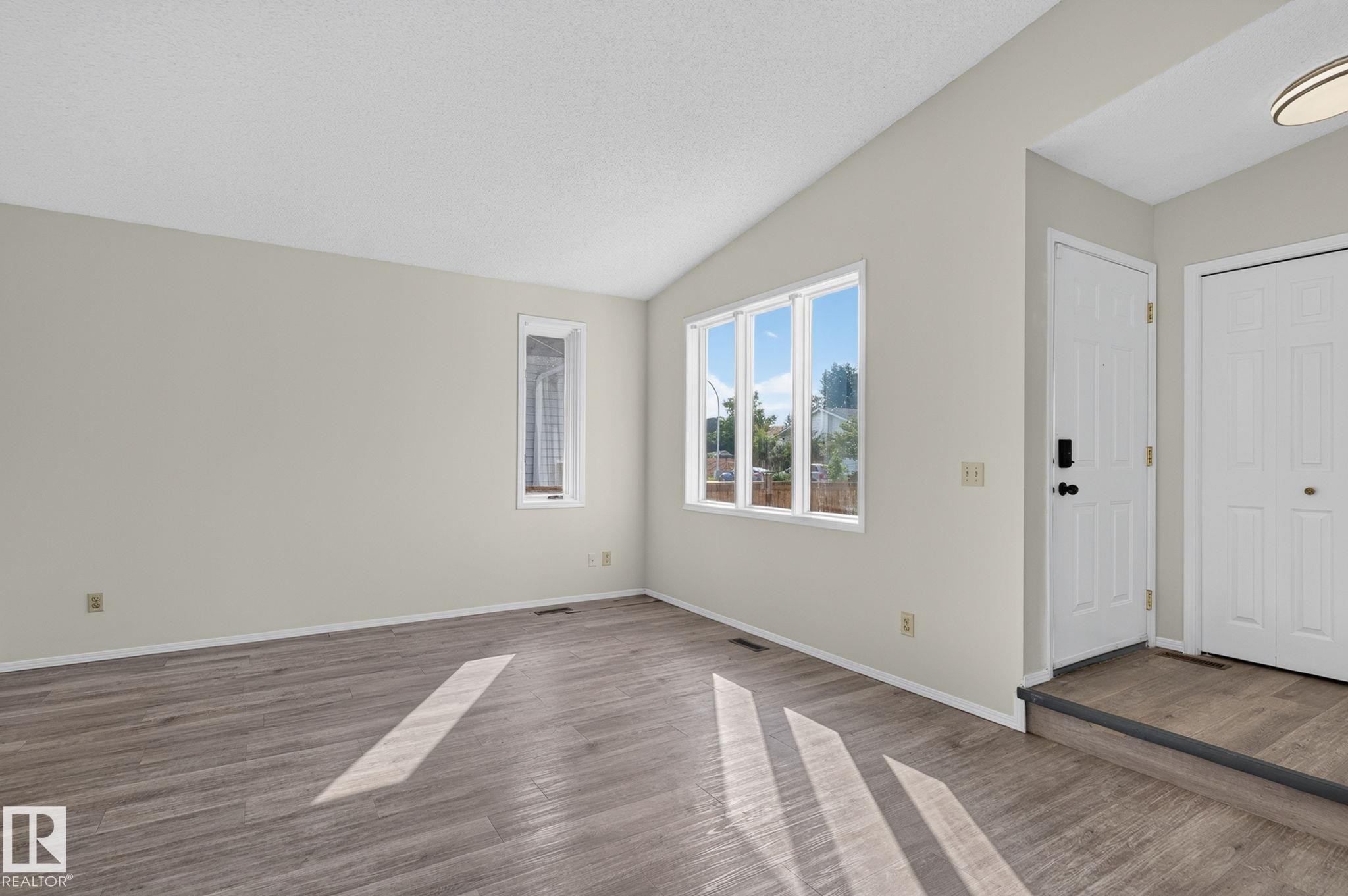 Living area featuring wood-finish flooring, vaulted ceiling, and neutral wall tones - 3722 34A Avenue Nw, Edmonton, AB - Indoor Photo Showing Other Room