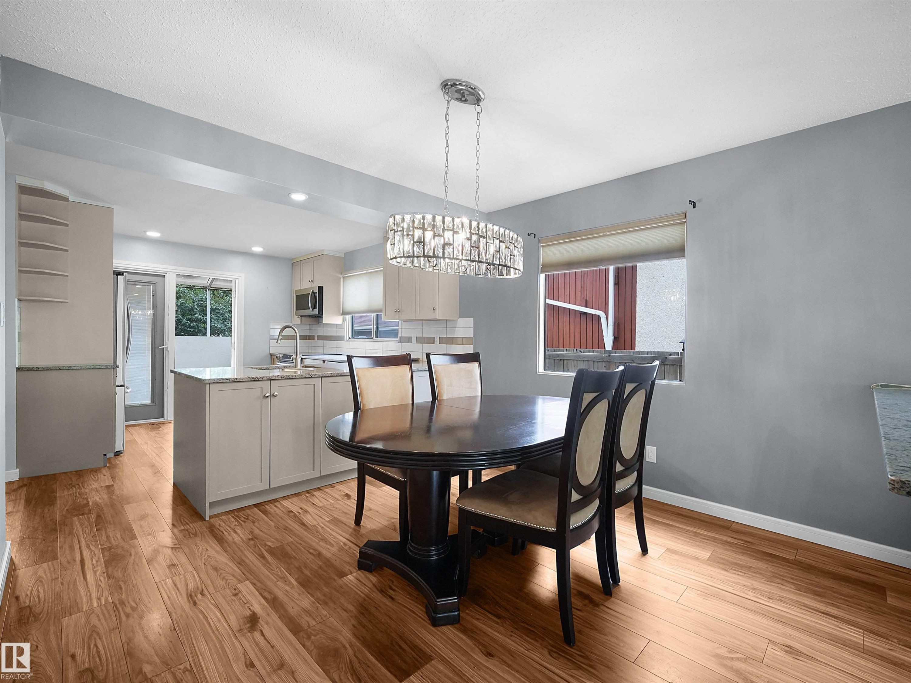Recessed lighting, wood-finish flooring, kitchen island with built-in cabinetry, stainless steel appliances, and a crystal-style chandelier - 7435 32 Avenue Nw, Edmonton, AB