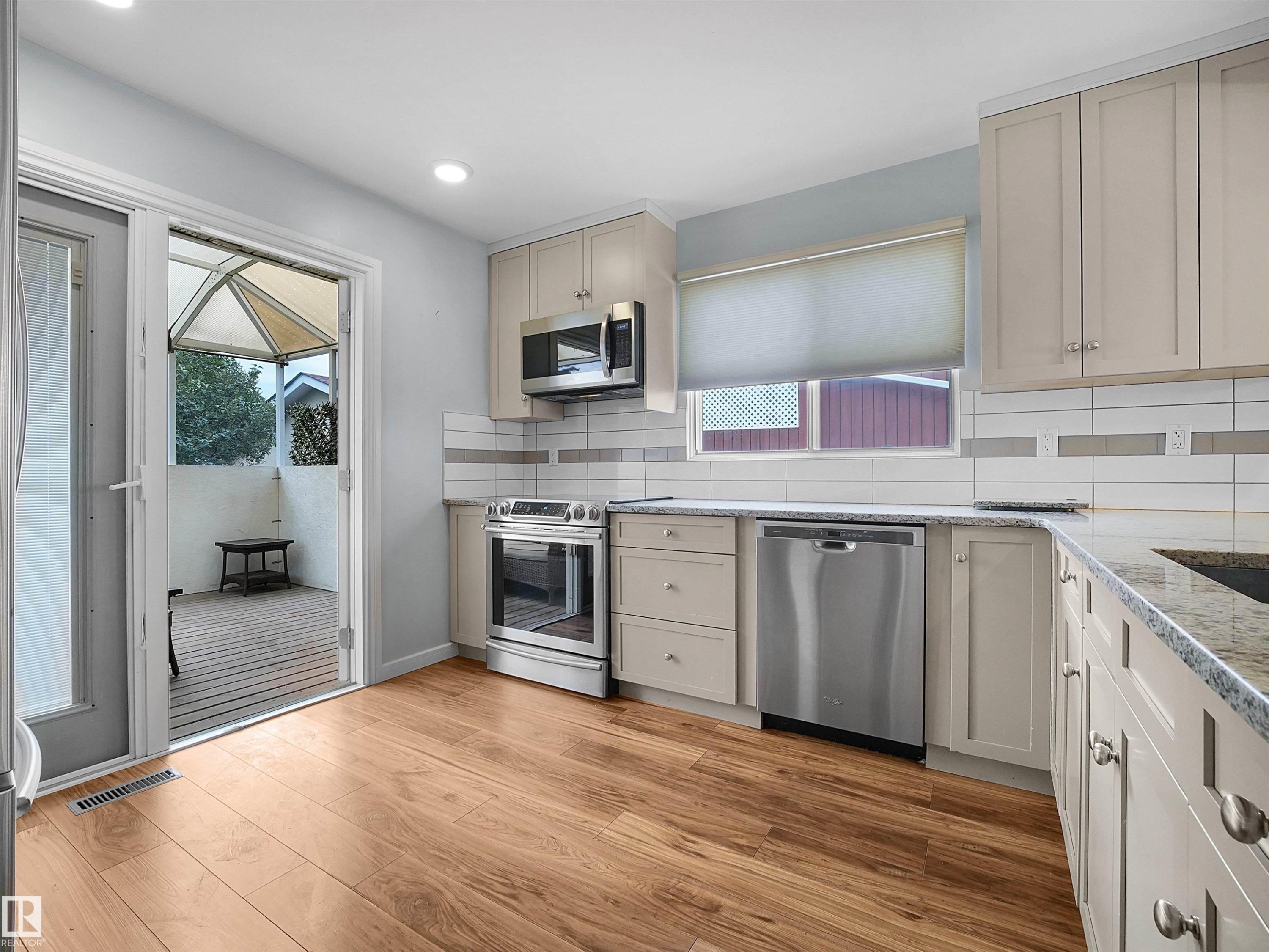 Wood-finish flooring, stainless steel appliances, light-toned cabinetry, and granite countertops - 7435 32 Avenue Nw, Edmonton, AB