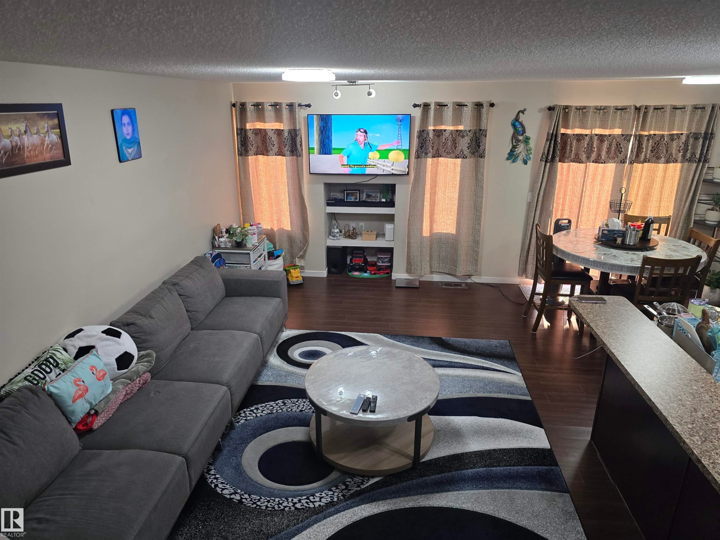 Wood-finish flooring throughout, featuring a dining area with a round table and chairs - 1474 33B Street Nw, Edmonton, AB