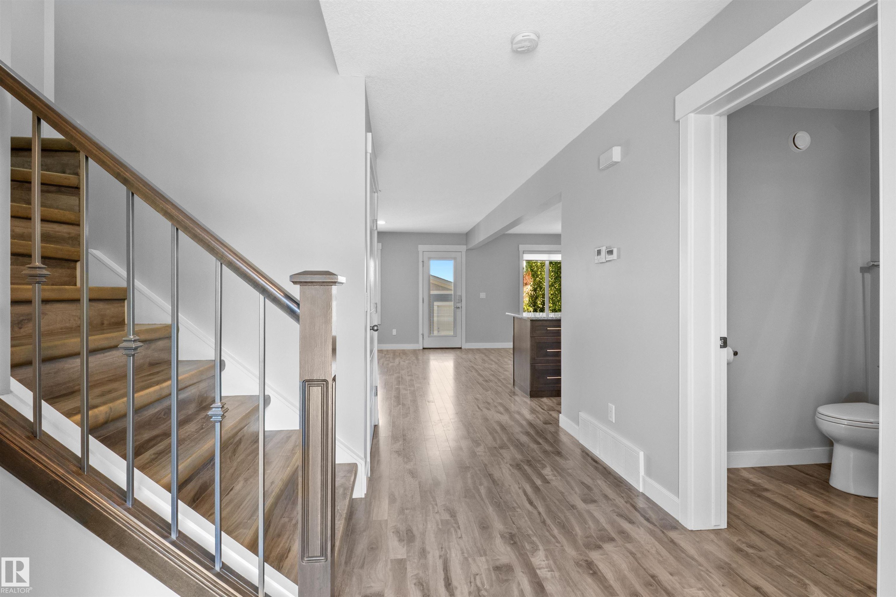 Wood-finish flooring throughout, staircase with wood risers and metal balusters, and a neutral wall color - 2585 Pegasus Boulevard Nw, Edmonton, AB