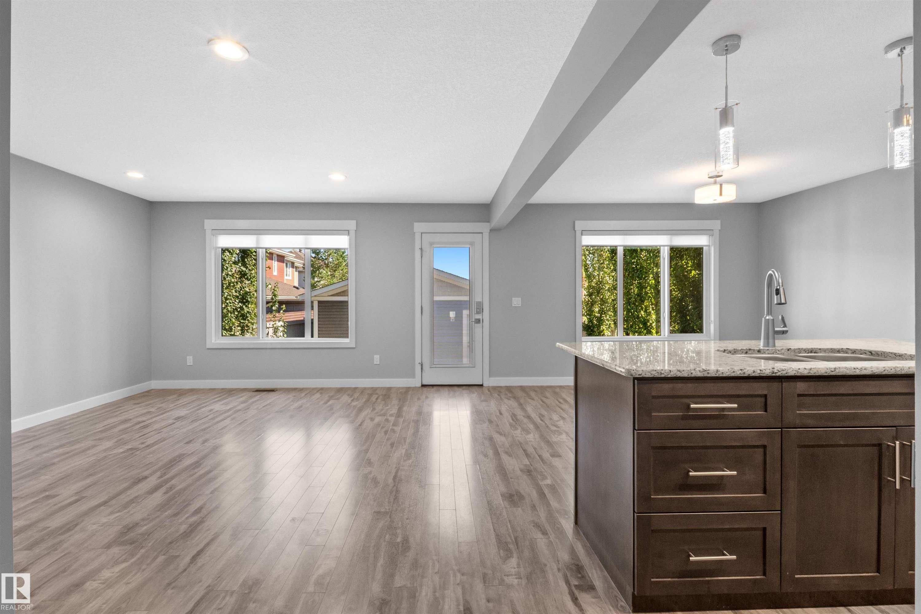 Open-concept living space with wood-finish flooring, recessed lighting, and ample natural light from multiple windows - 2585 Pegasus Boulevard Nw, Edmonton, AB