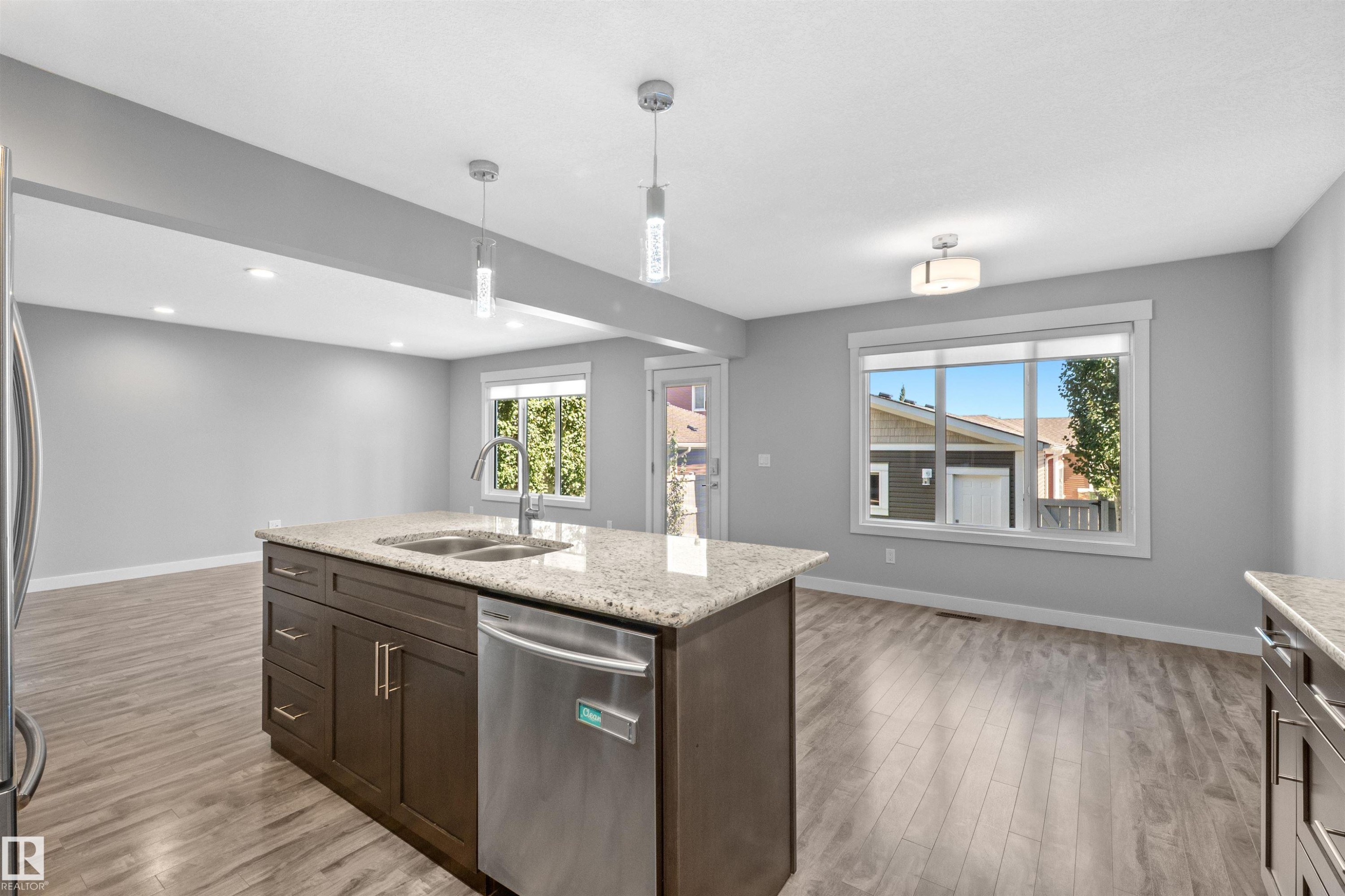 Kitchen island featuring a double-basin sink, stainless steel dishwasher, and granite countertop - 2585 Pegasus Boulevard Nw, Edmonton, AB