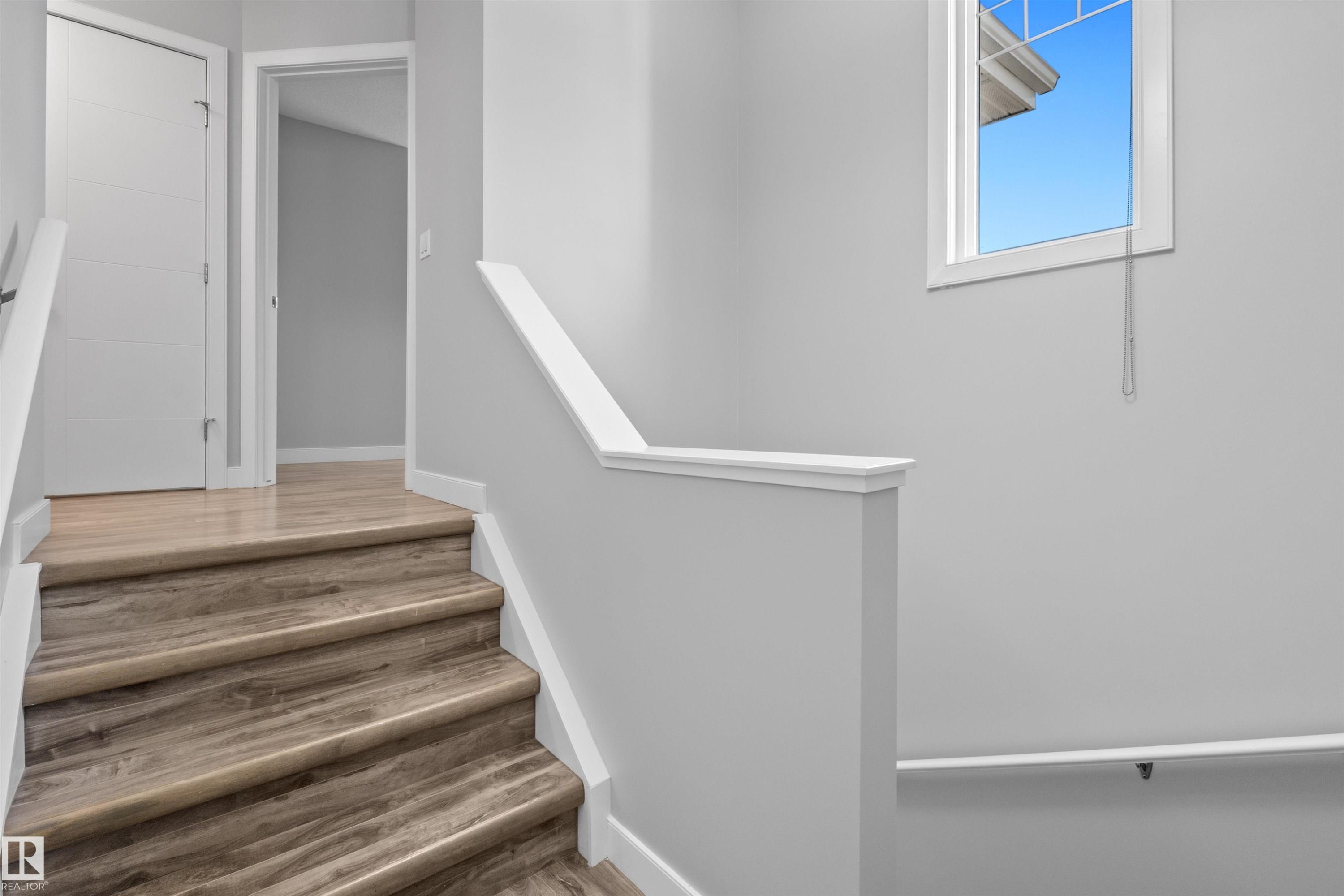 Staircase with wood-finish treads and risers, white railing, and bright overhead window - 2585 Pegasus Boulevard Nw, Edmonton, AB