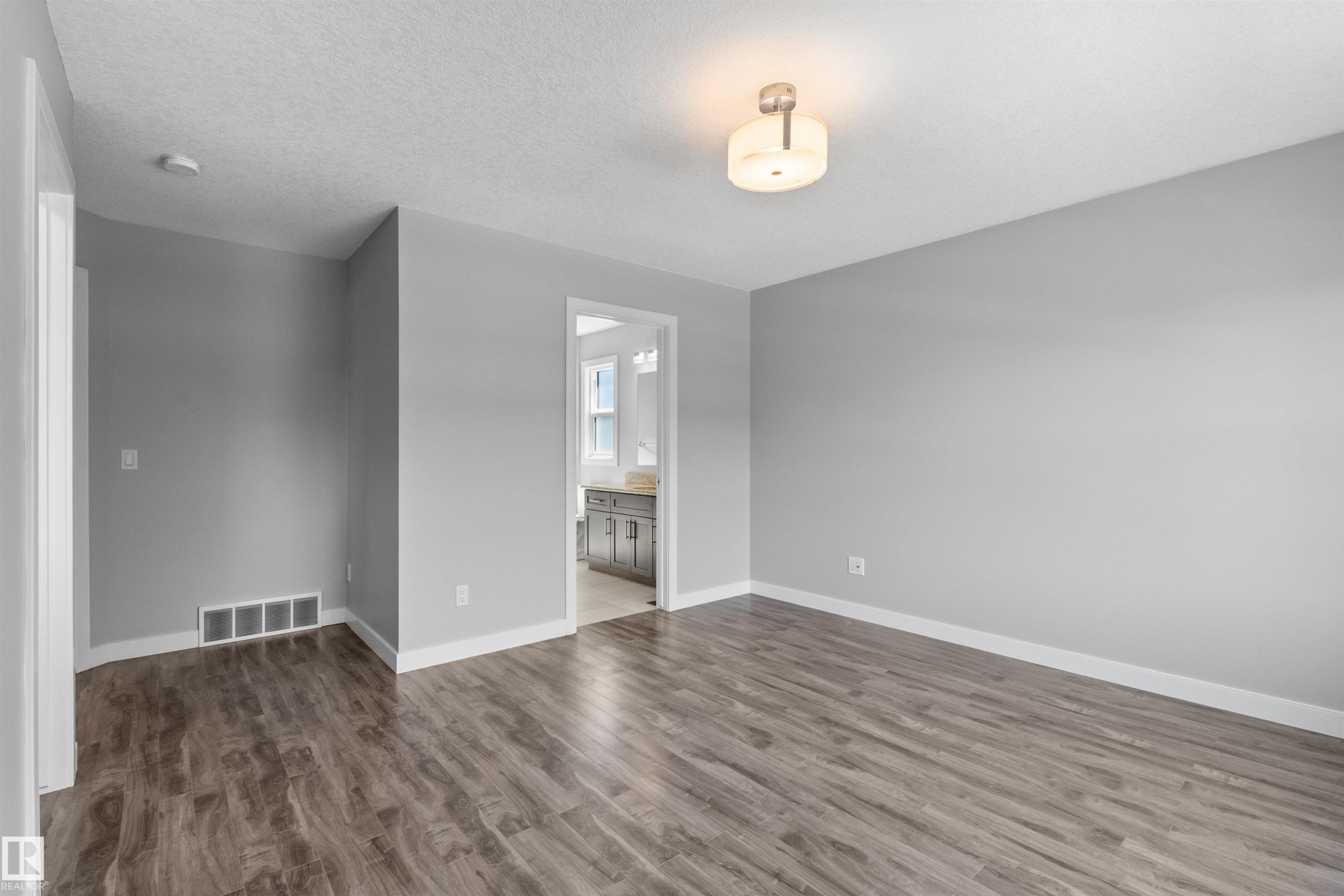 Wood-finish flooring, light gray wall paint, and a semi-flush mount ceiling light fixture - 2585 Pegasus Boulevard Nw, Edmonton, AB