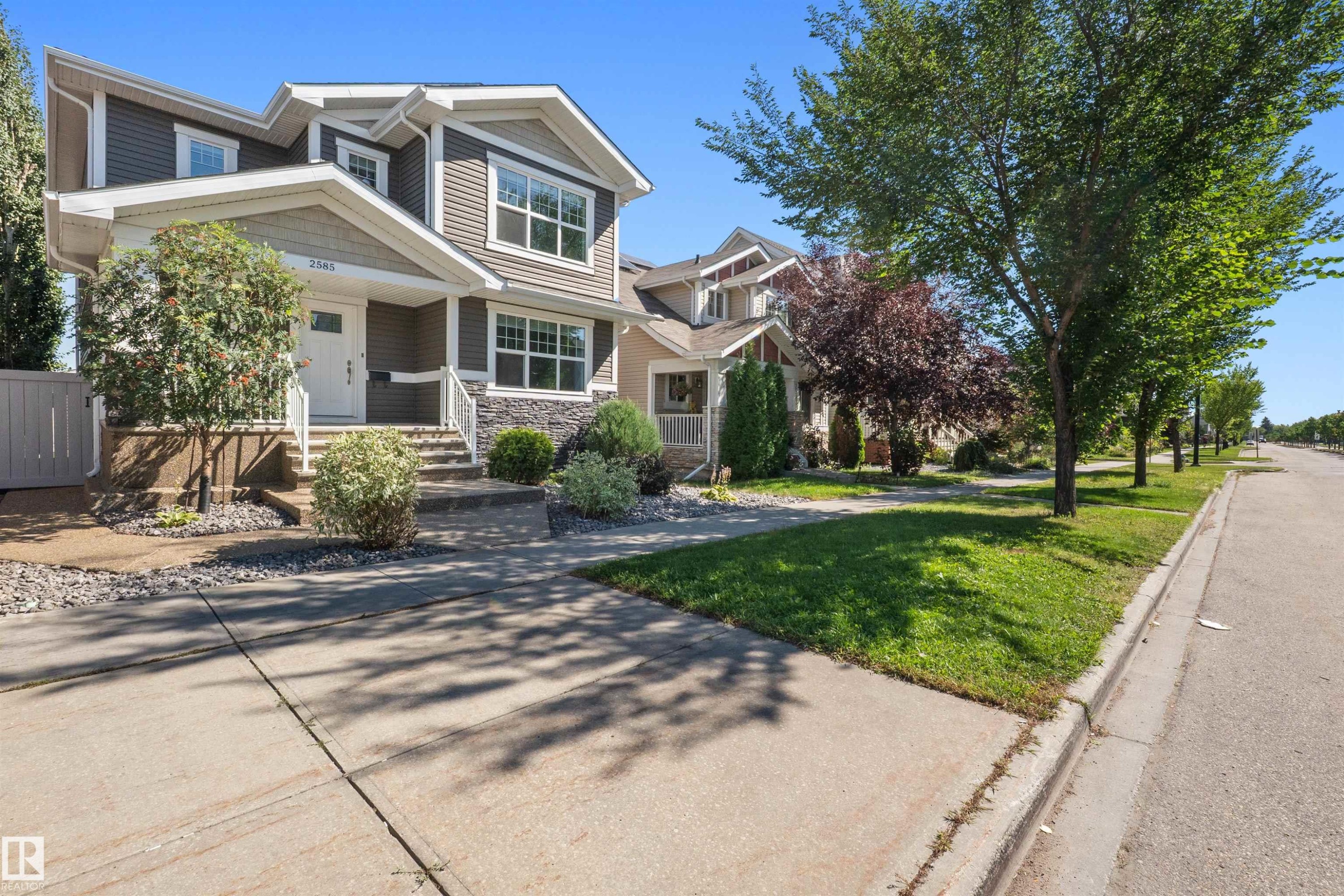 Two-story exterior with siding and stone accents, featuring a covered front porch and concrete walkway - 2585 Pegasus Boulevard Nw, Edmonton, AB