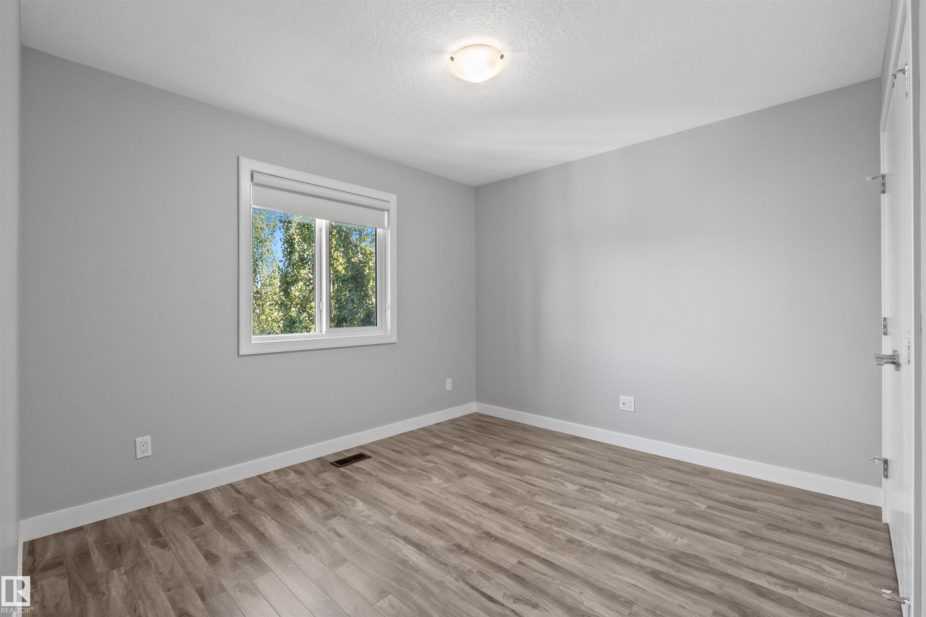 Wood-finish flooring, neutral wall color, and a window with a roller shade - 2585 Pegasus Boulevard Nw, Edmonton, AB