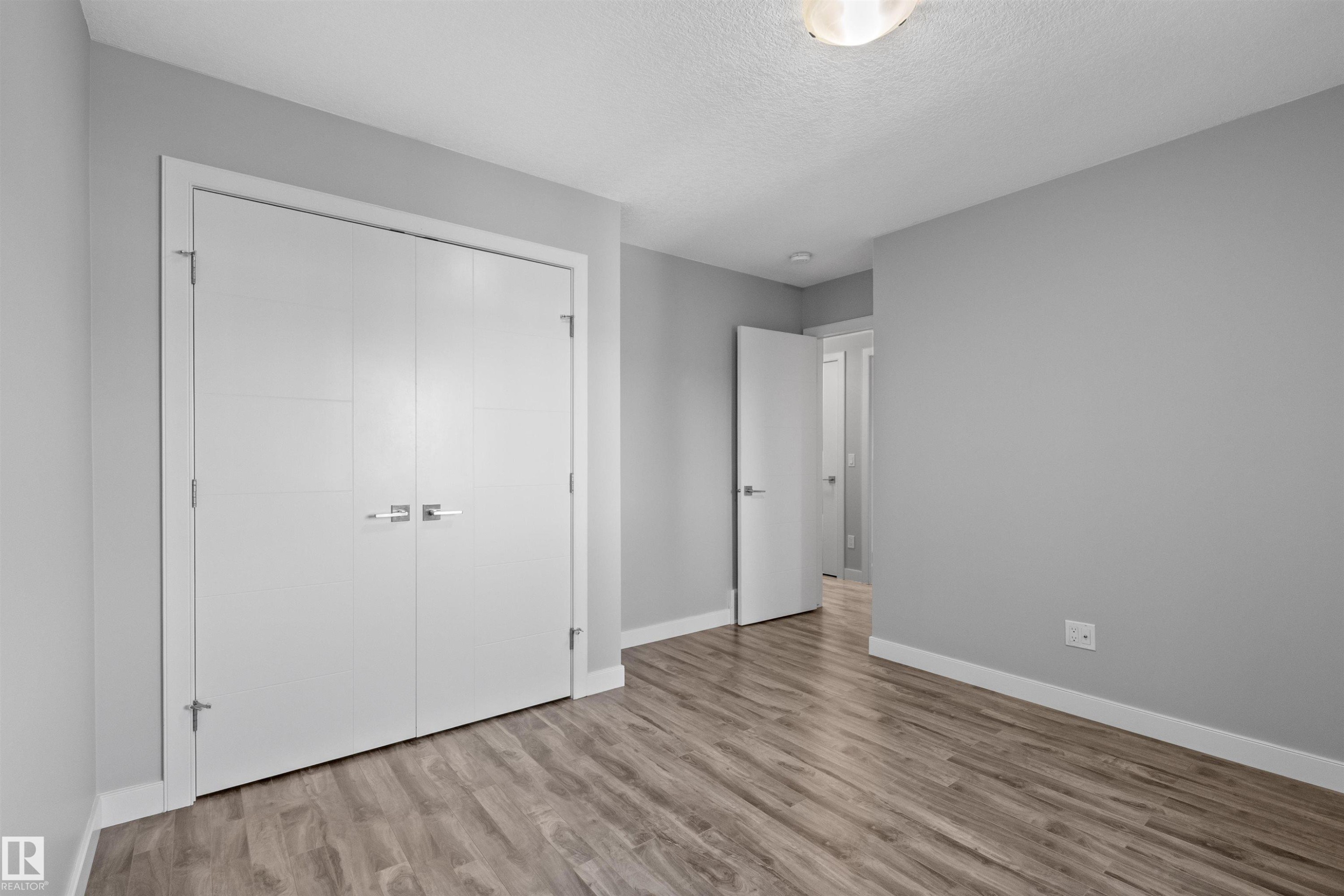 Wood-finish flooring with light gray walls, white trim, and a semi-flush mount ceiling light - 2585 Pegasus Boulevard Nw, Edmonton, AB