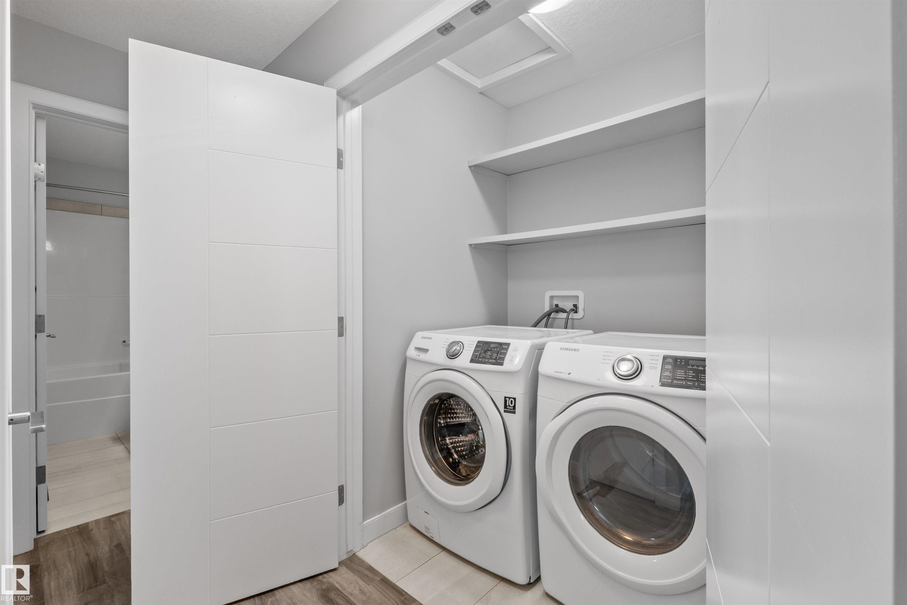 Laundry area featuring a stackable washer and dryer, integrated shelving, and tile flooring - 2585 Pegasus Boulevard Nw, Edmonton, AB