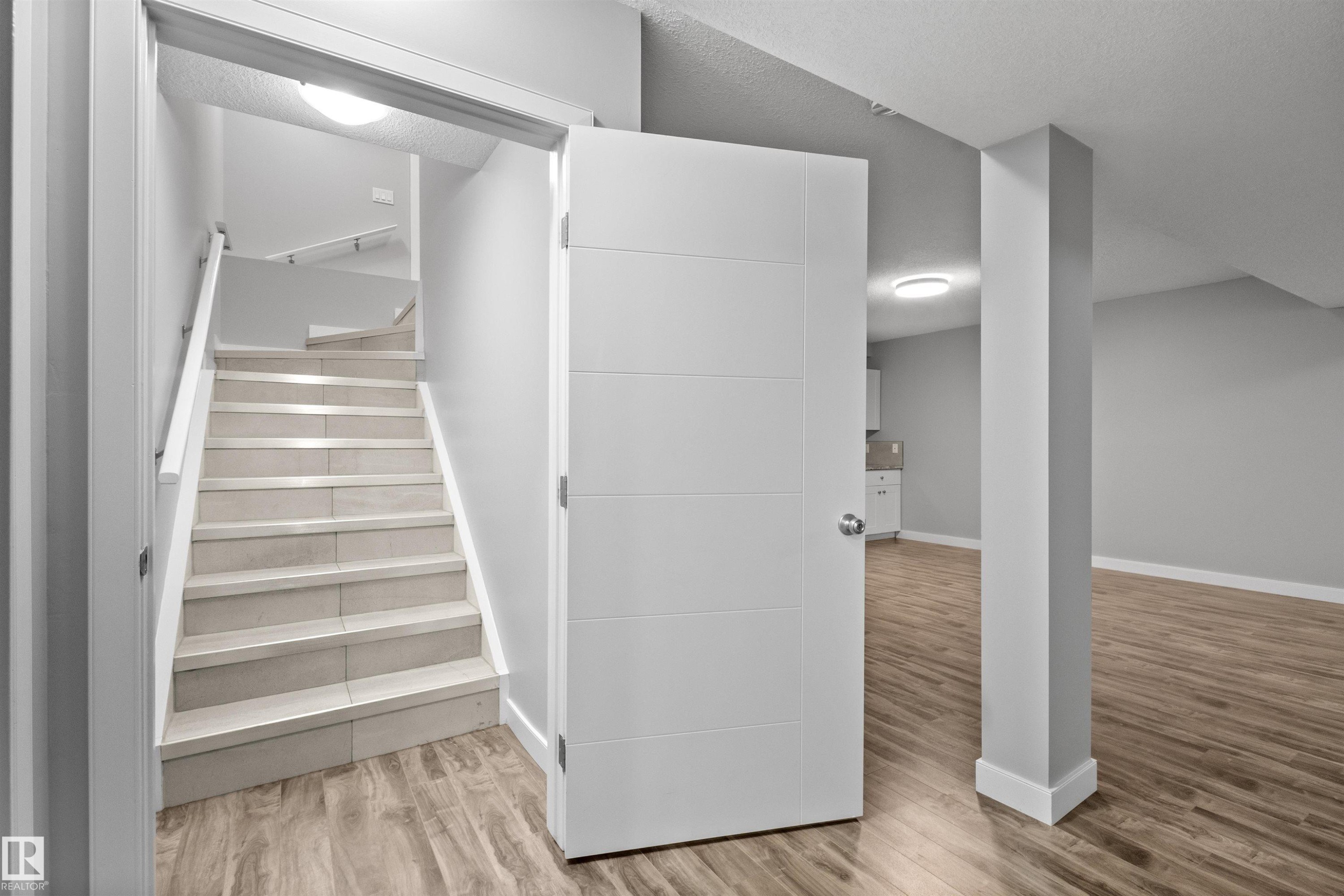 Tiled staircase with white handrail and wood-finish flooring - 2585 Pegasus Boulevard Nw, Edmonton, AB