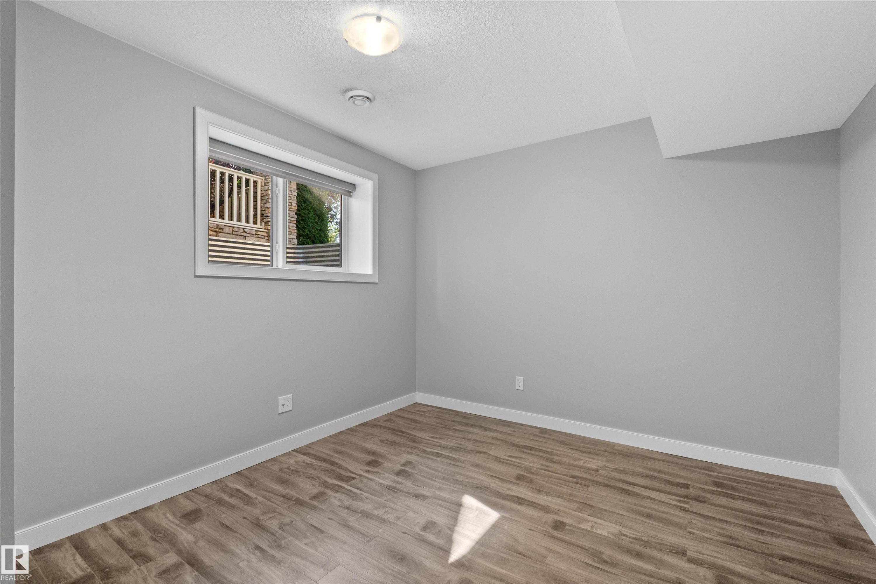 Recessed window with roller shade, wood-finish flooring, and white trim - 2585 Pegasus Boulevard Nw, Edmonton, AB