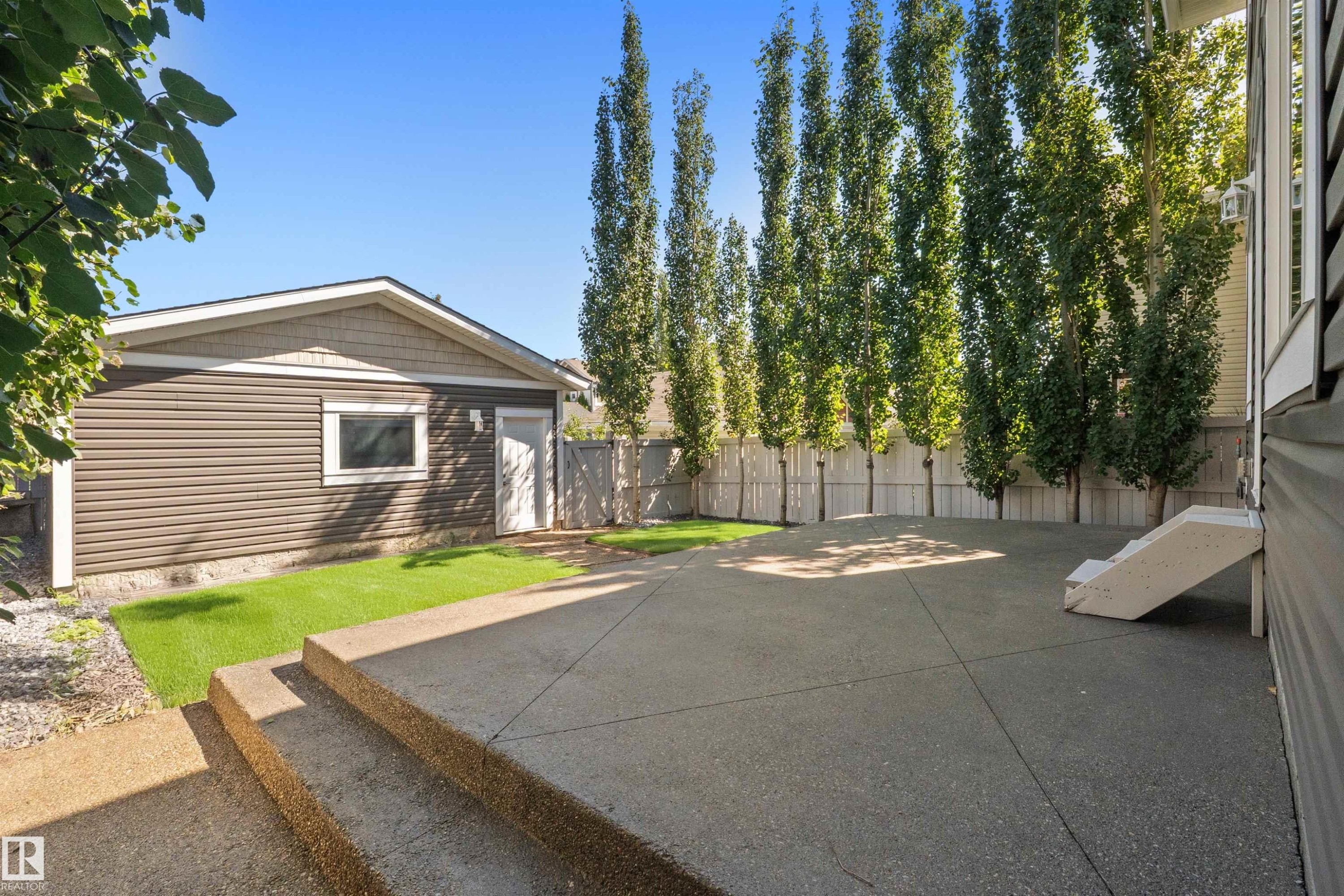 Expansive concrete patio area with integrated steps, detached garage, and a privacy fence - 2585 Pegasus Boulevard Nw, Edmonton, AB