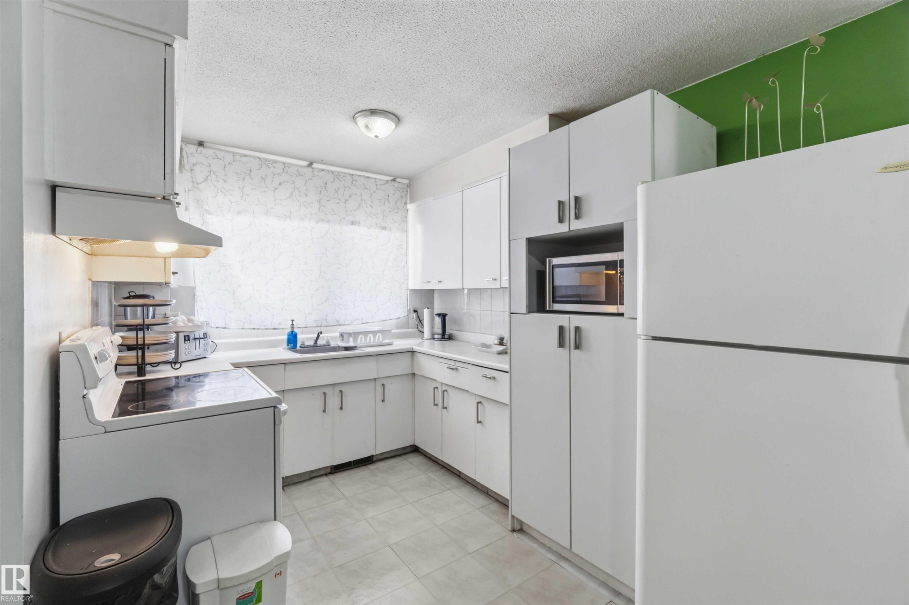 White cabinetry with integrated microwave, white tiled flooring, and a white countertop - 13408 67 Street Nw, Edmonton, AB
