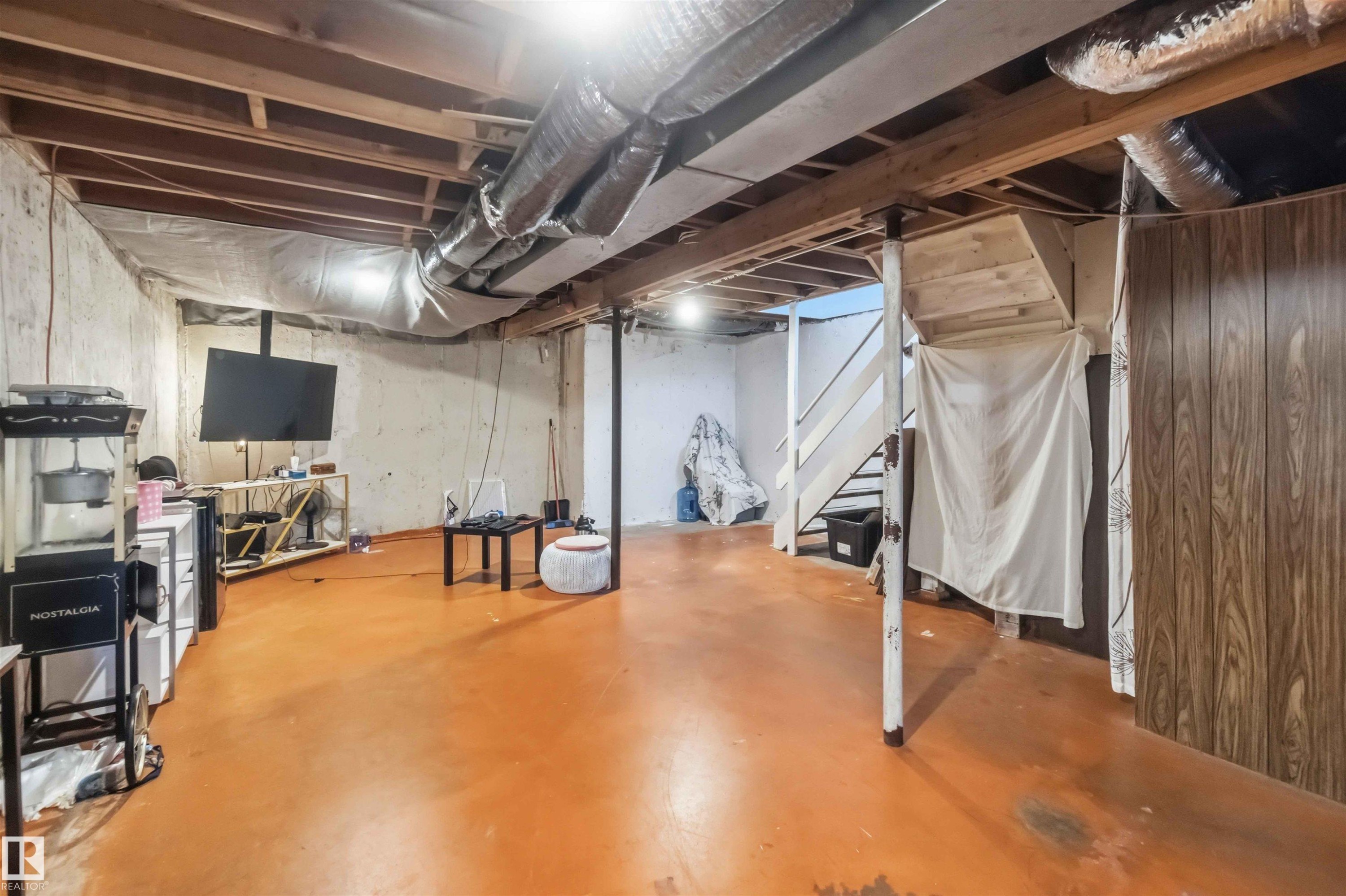 Exposed ceiling joists with visible ductwork, concrete flooring, and painted cinder block walls - 13408 67 Street Nw, Edmonton, AB