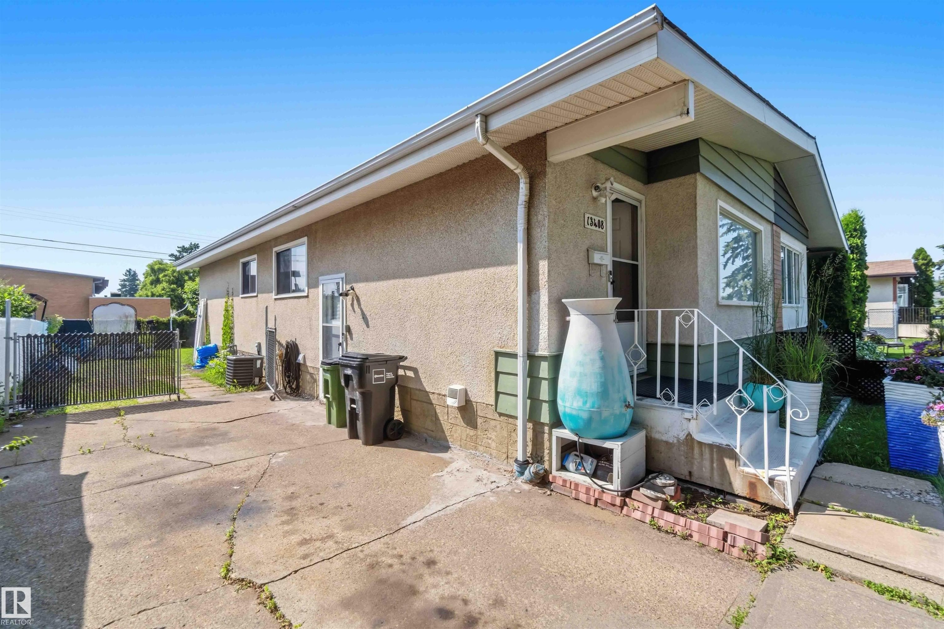 Stucco exterior with a covered entry, white railing, and a concrete driveway - 13408 67 Street Nw, Edmonton, AB