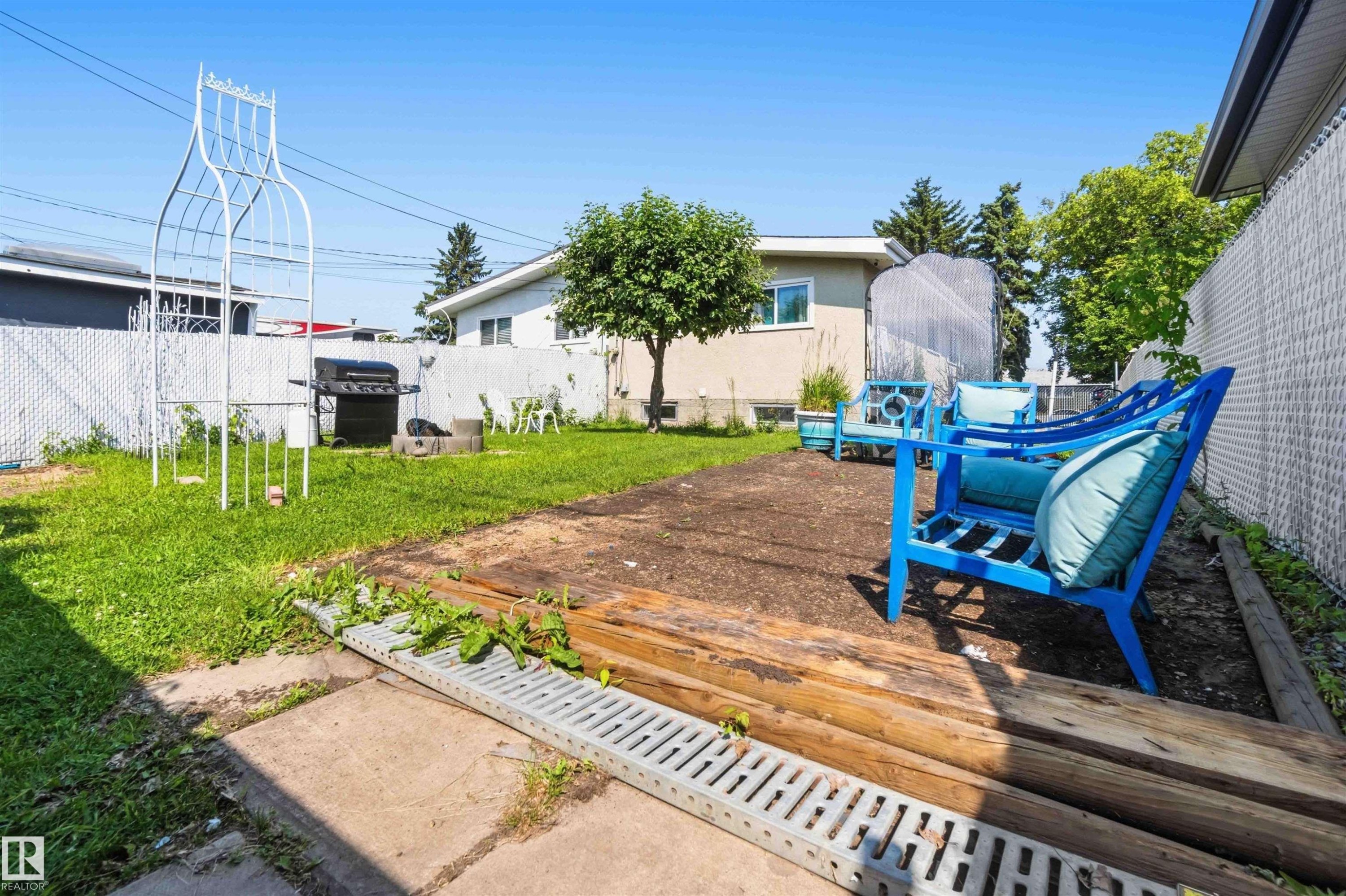 Expansive backyard with a level lawn, concrete patio, and a dedicated wooden patio area - 13408 67 Street Nw, Edmonton, AB