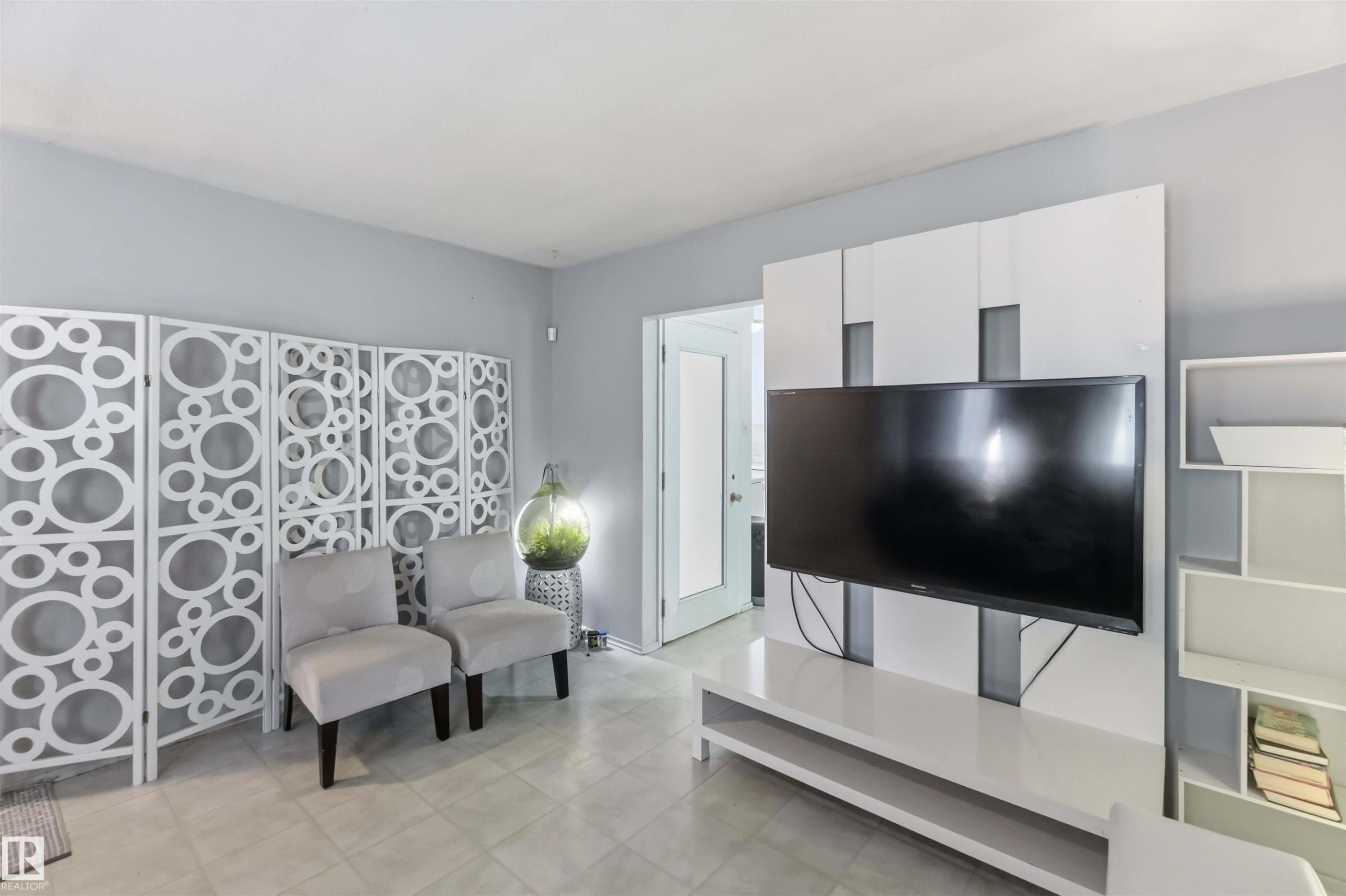 Tile flooring, light gray wall paint, white room divider with circular pattern, white built-in media console, white open shelving unit - 13408 67 Street Nw, Edmonton, AB
