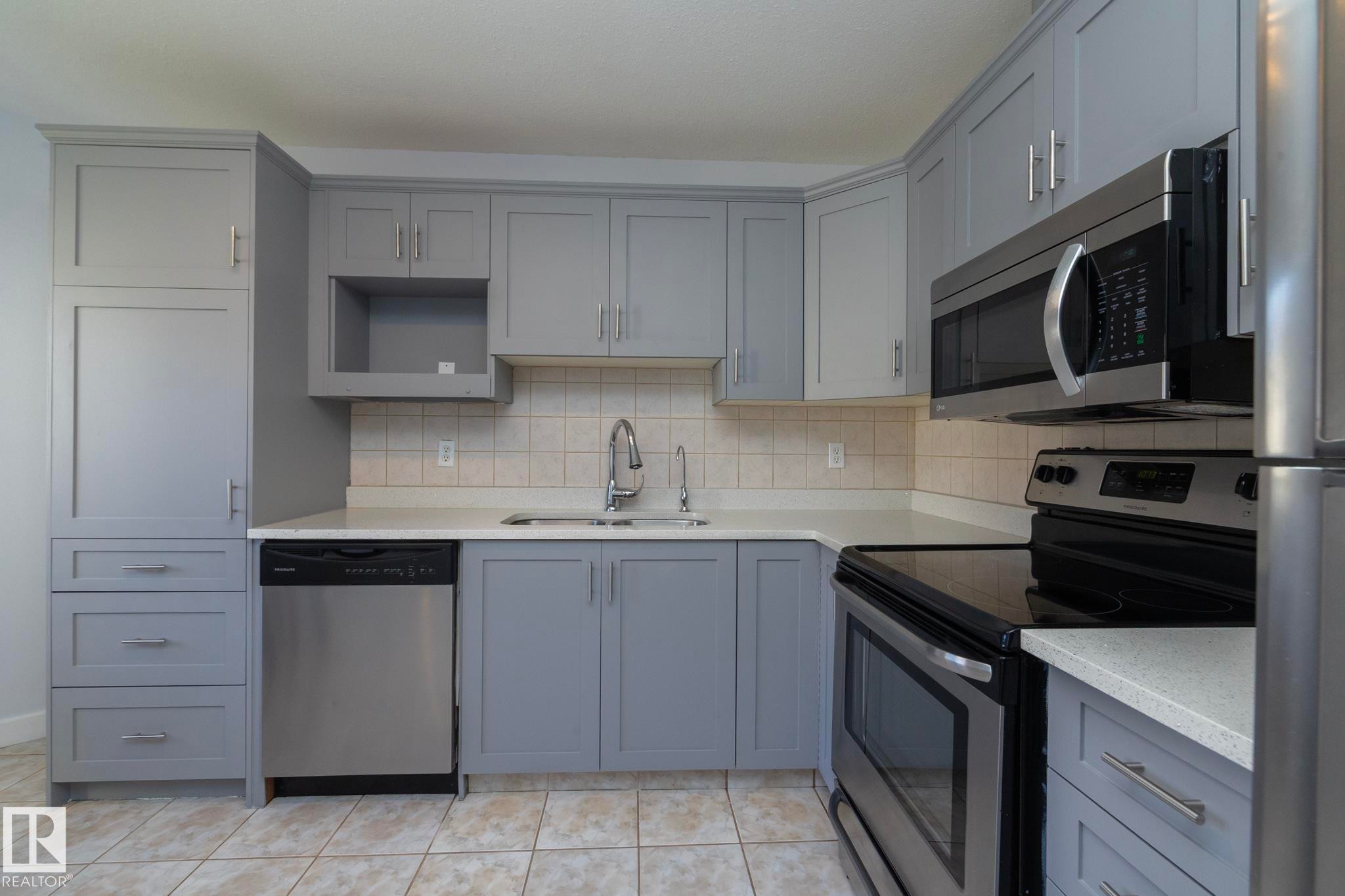 Kitchen featuring light gray cabinetry, white countertops, tile backsplash, and stainless steel appliances - #37 3811 85 St Nw, Edmonton, AB