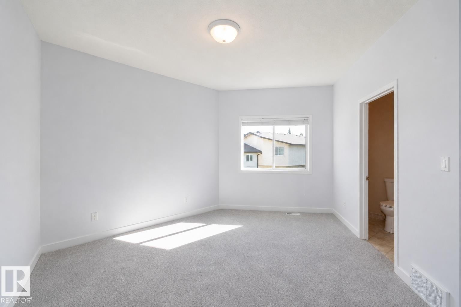 Light gray wall paint, gray carpeting, single window, flush mount ceiling light fixture, white trim - #37 3811 85 St Nw, Edmonton, AB