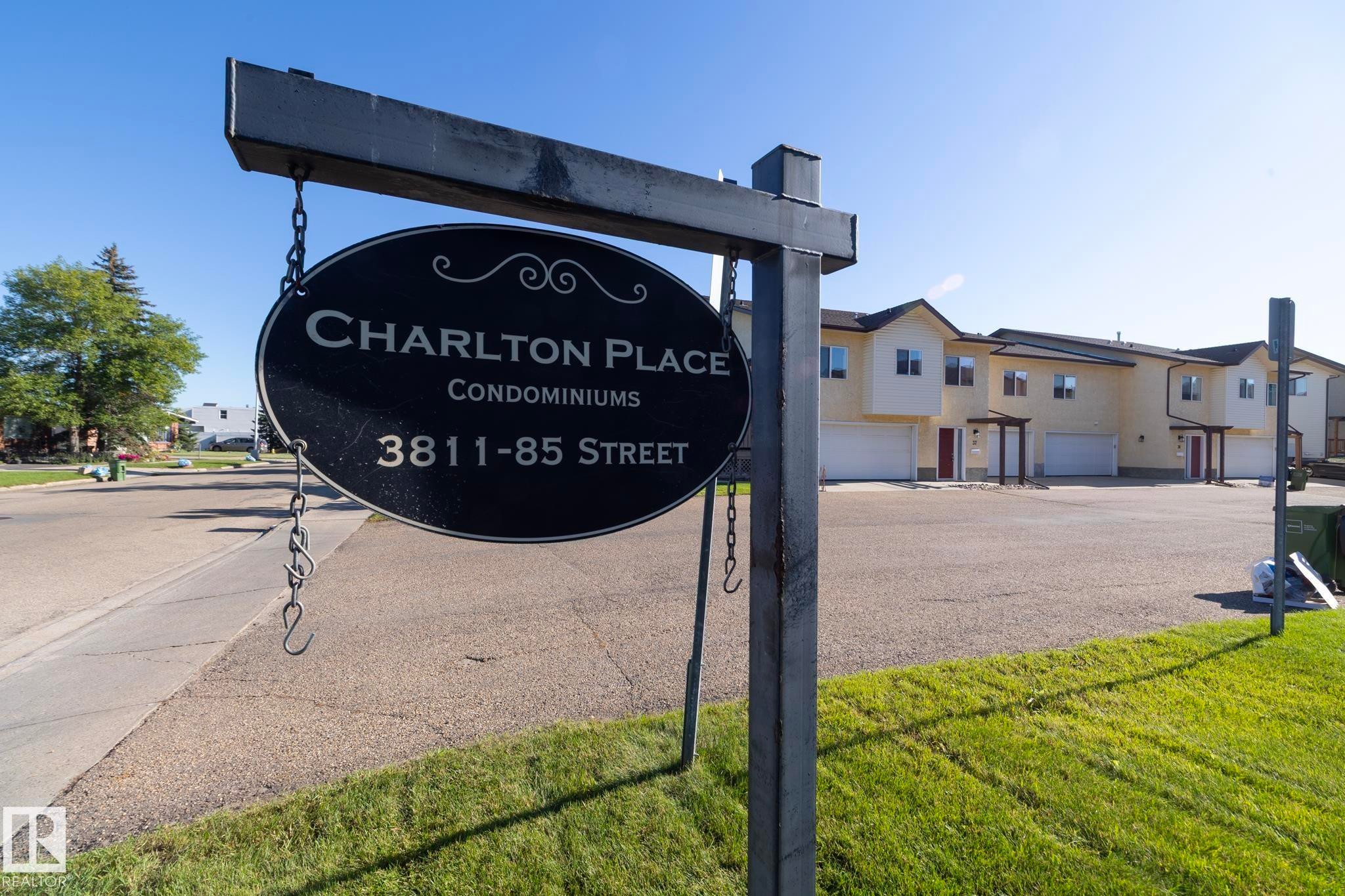 Charlton Place Condominiums sign, providing street address information, with a multi-unit residential building in the background - #37 3811 85 St Nw, Edmonton, AB