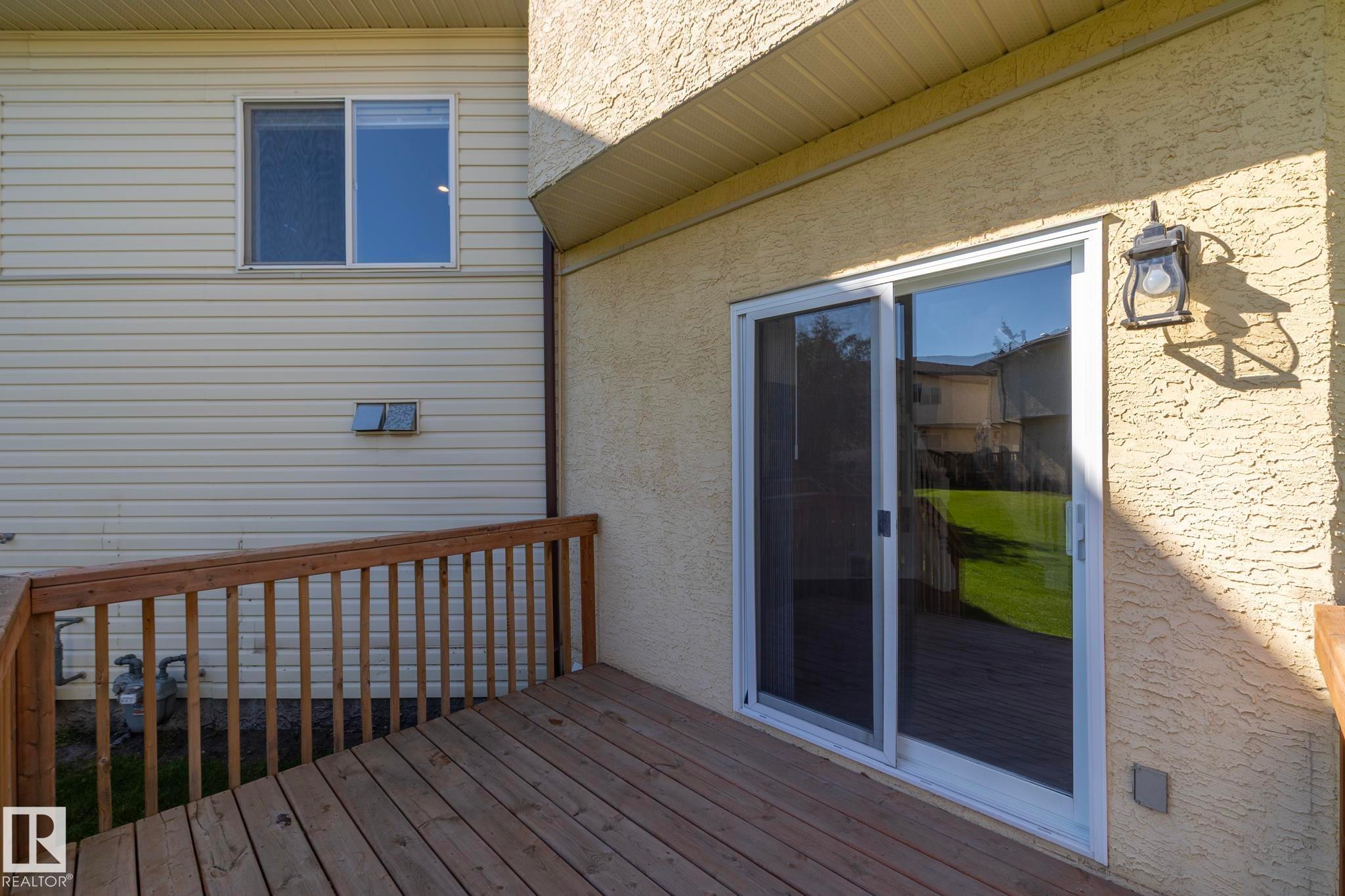 Wood-finish deck with a wooden railing, directly accessible through a sliding glass door - #37 3811 85 St Nw, Edmonton, AB