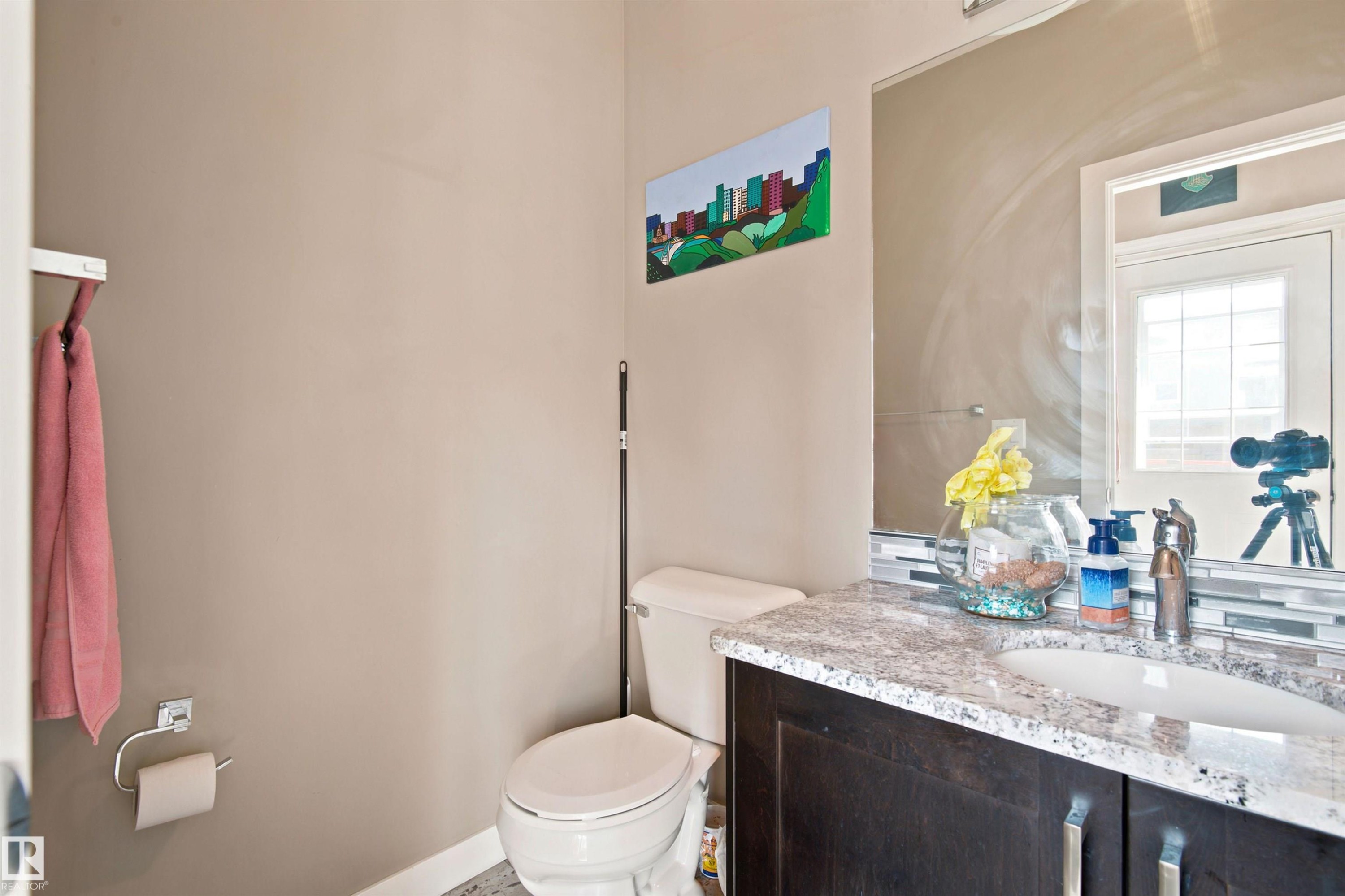 Vanity with granite-style countertop, dark wood-finish cabinetry with silver hardware, and a ceramic undermount sink - 10833 63 Avenue Nw, Edmonton, AB