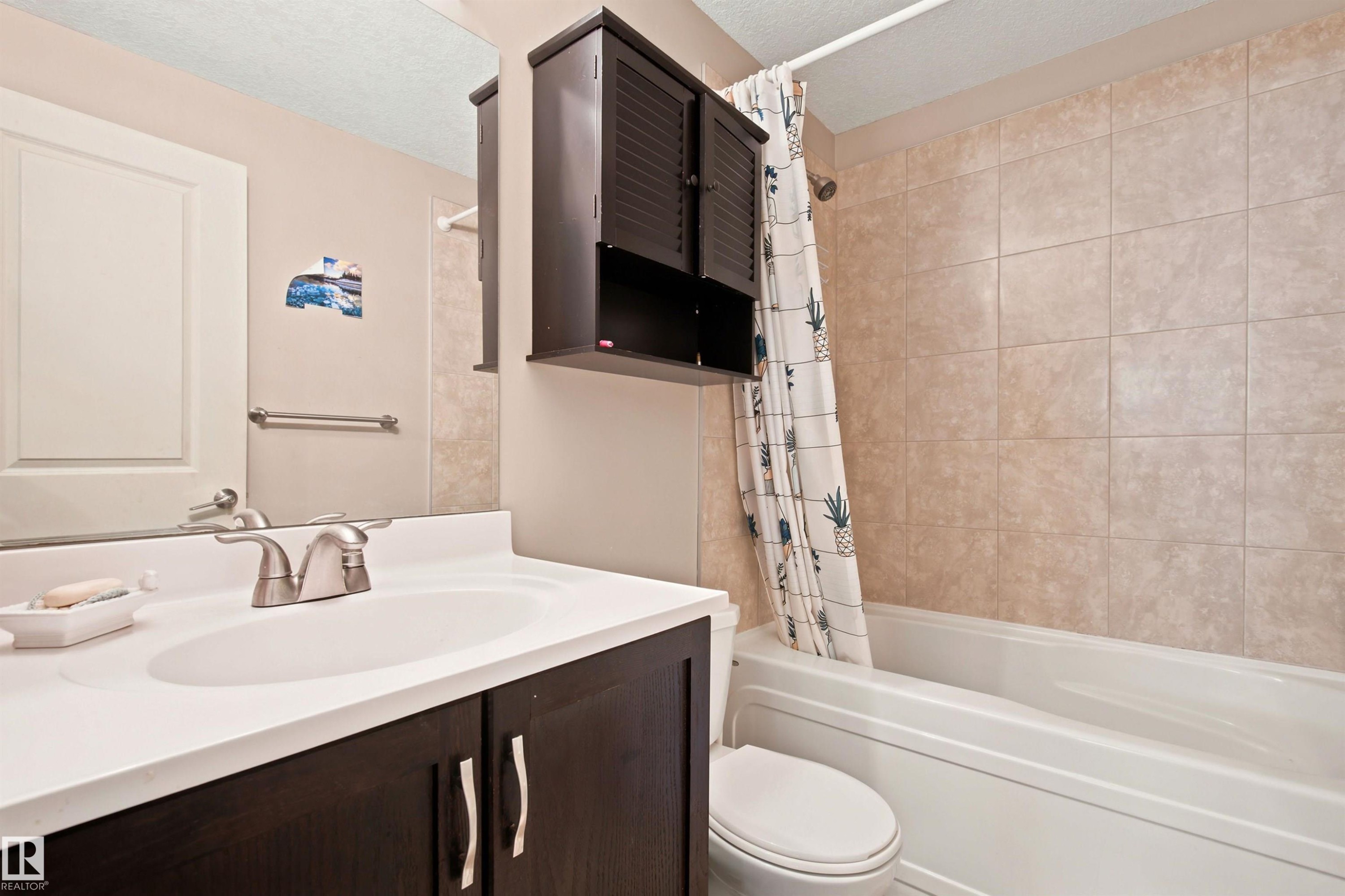 Integrated vanity with a single basin sink, brushed nickel faucet, and dark wood-finish cabinetry - 10833 63 Avenue Nw, Edmonton, AB