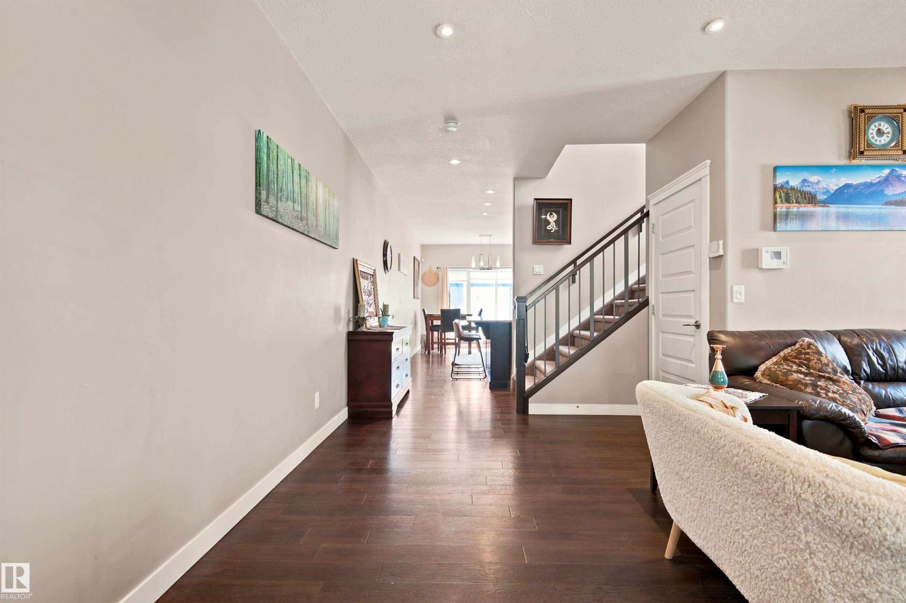 Dark wood-finish flooring throughout, recessed lighting, and a staircase with a dark wood handrail and metal spindles - 10833 63 Avenue Nw, Edmonton, AB