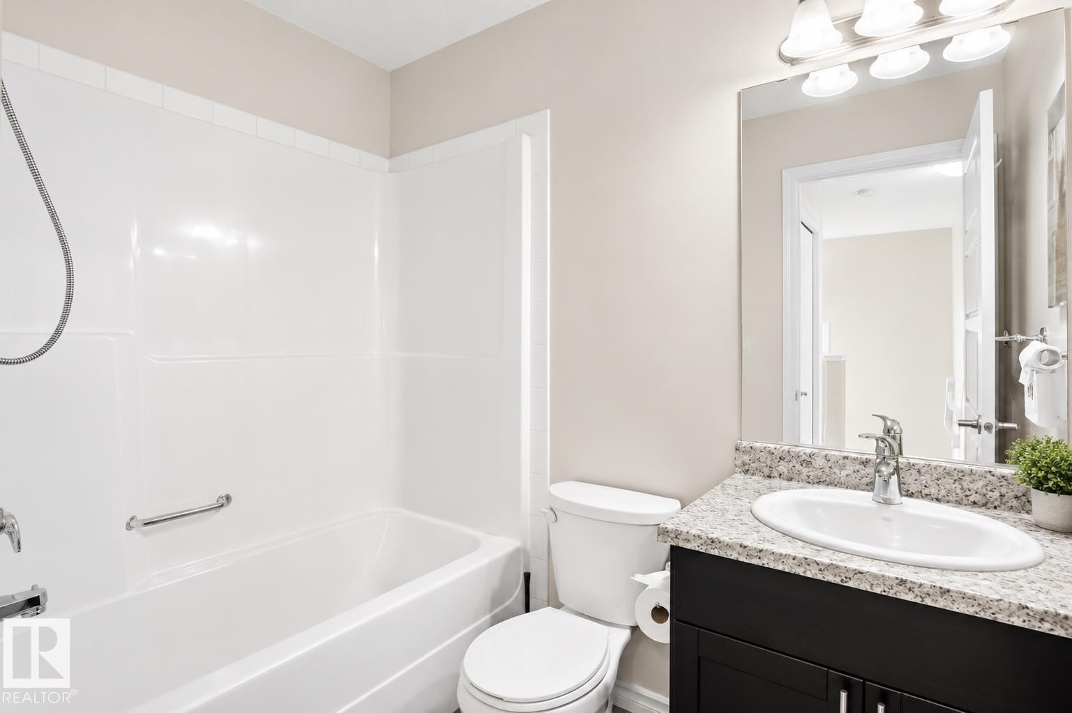White tub and shower combination with a grab bar, black vanity with a granite countertop, oval sink, and a chrome faucet - 445 Watt Boulevard Sw, Edmonton, AB