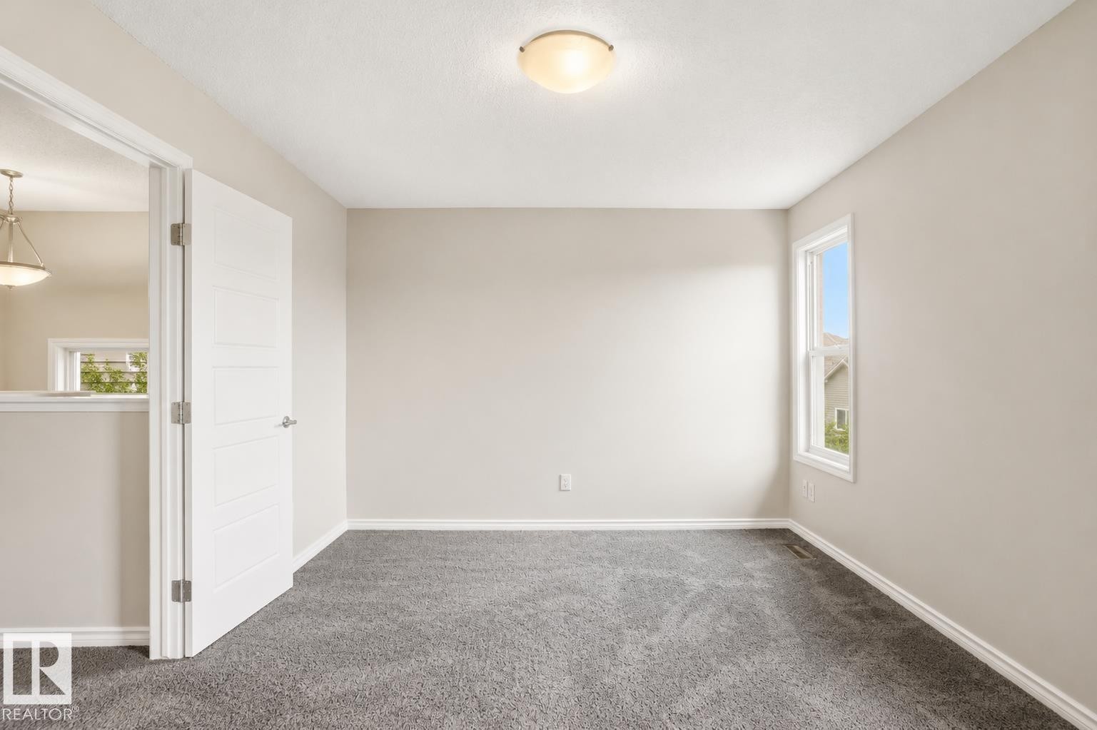 Neutral wall paint, gray carpet flooring, white trim, single-pane window, and flush mount lighting - 445 Watt Boulevard Sw, Edmonton, AB