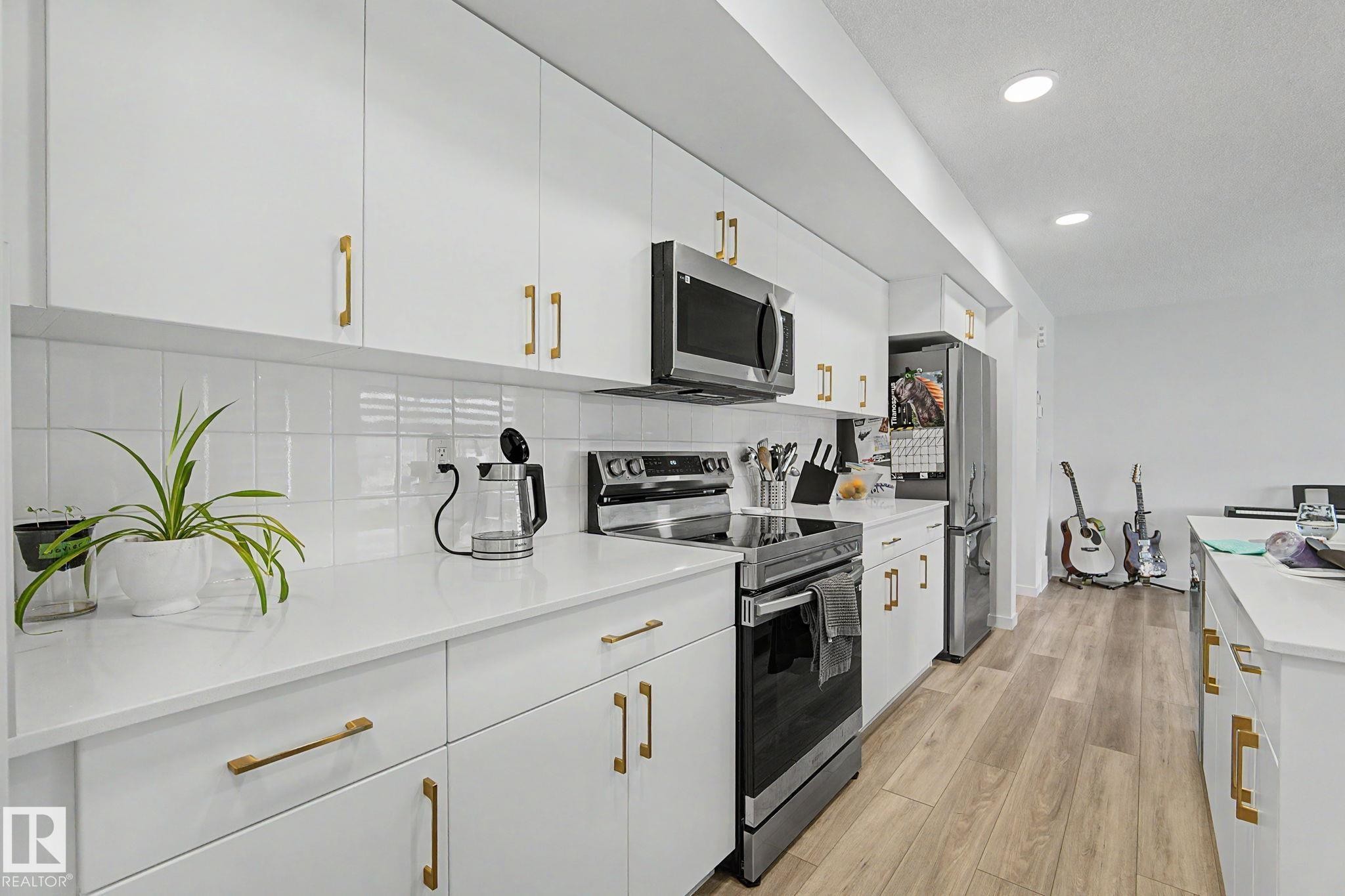 Modern kitchen with white cabinetry and gold-finish hardware - #12 905 172 St Sw, Edmonton, AB - Indoor Photo Showing Kitchen