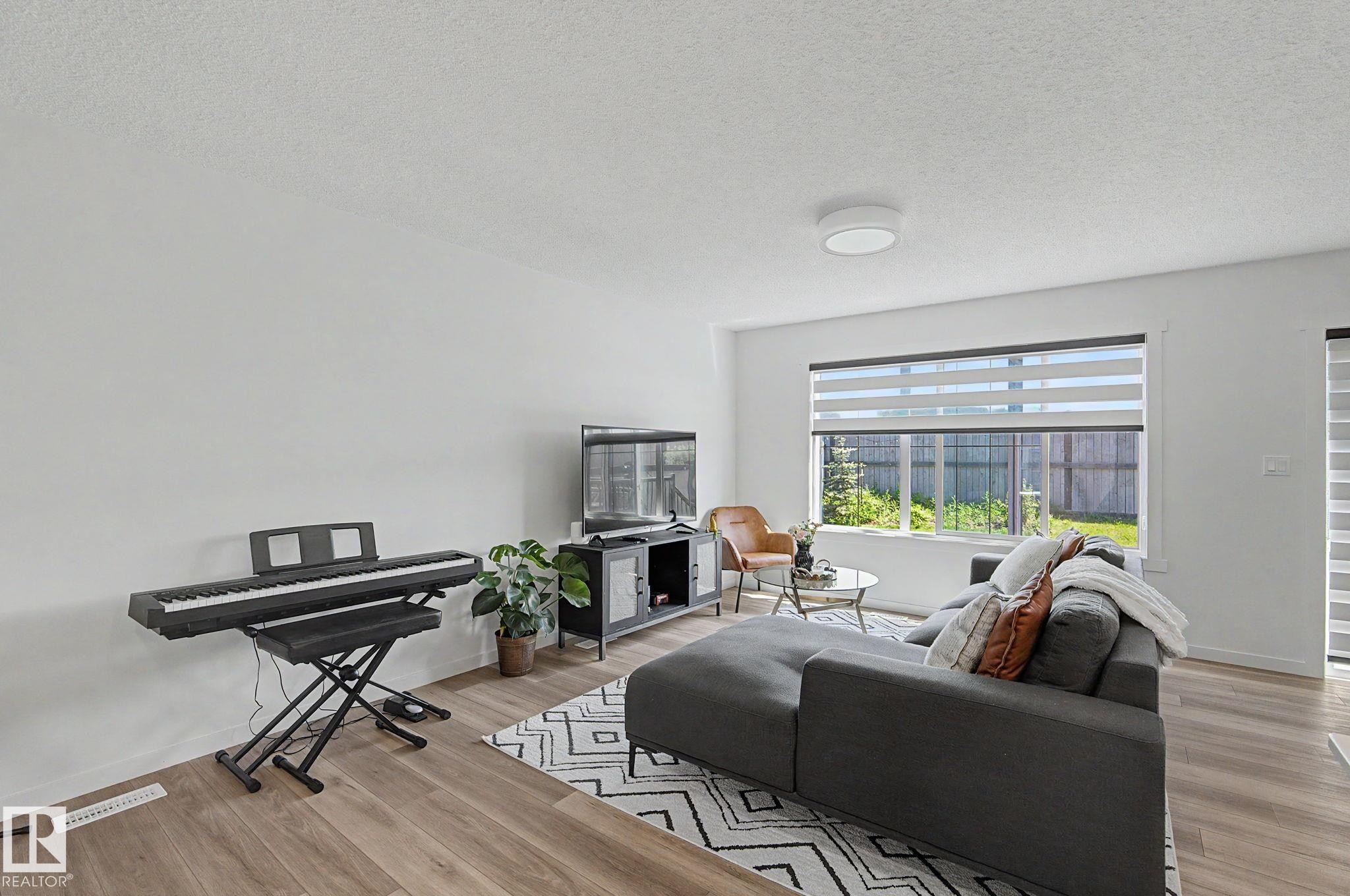 Living area featuring wood-finish flooring, a large window with privacy blinds, and recessed lighting - #12 905 172 St Sw, Edmonton, AB - Indoor