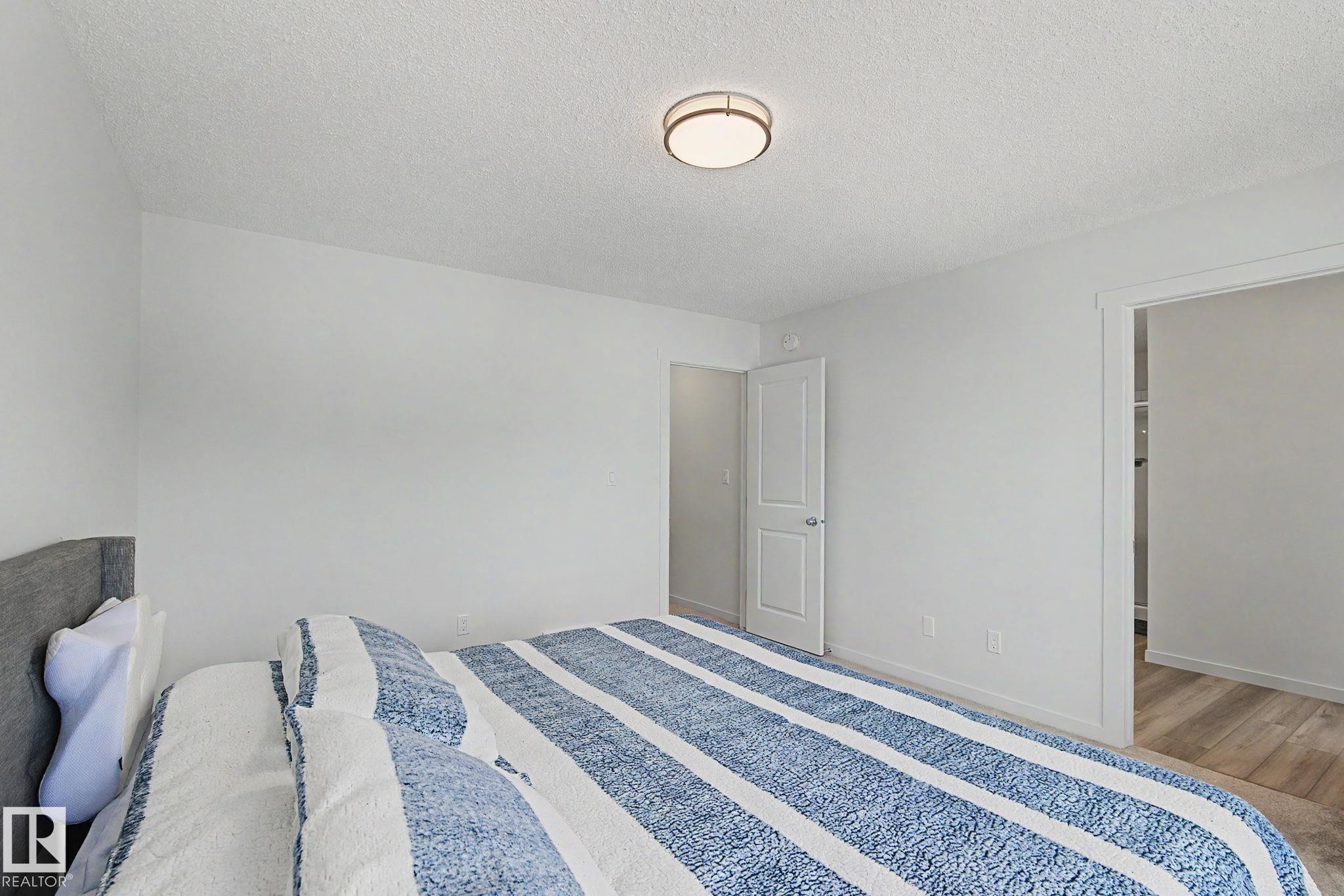 Bright interior space with white walls and a contemporary flush-mount ceiling light - #12 905 172 St Sw, Edmonton, AB - Indoor Photo Showing Bedroom