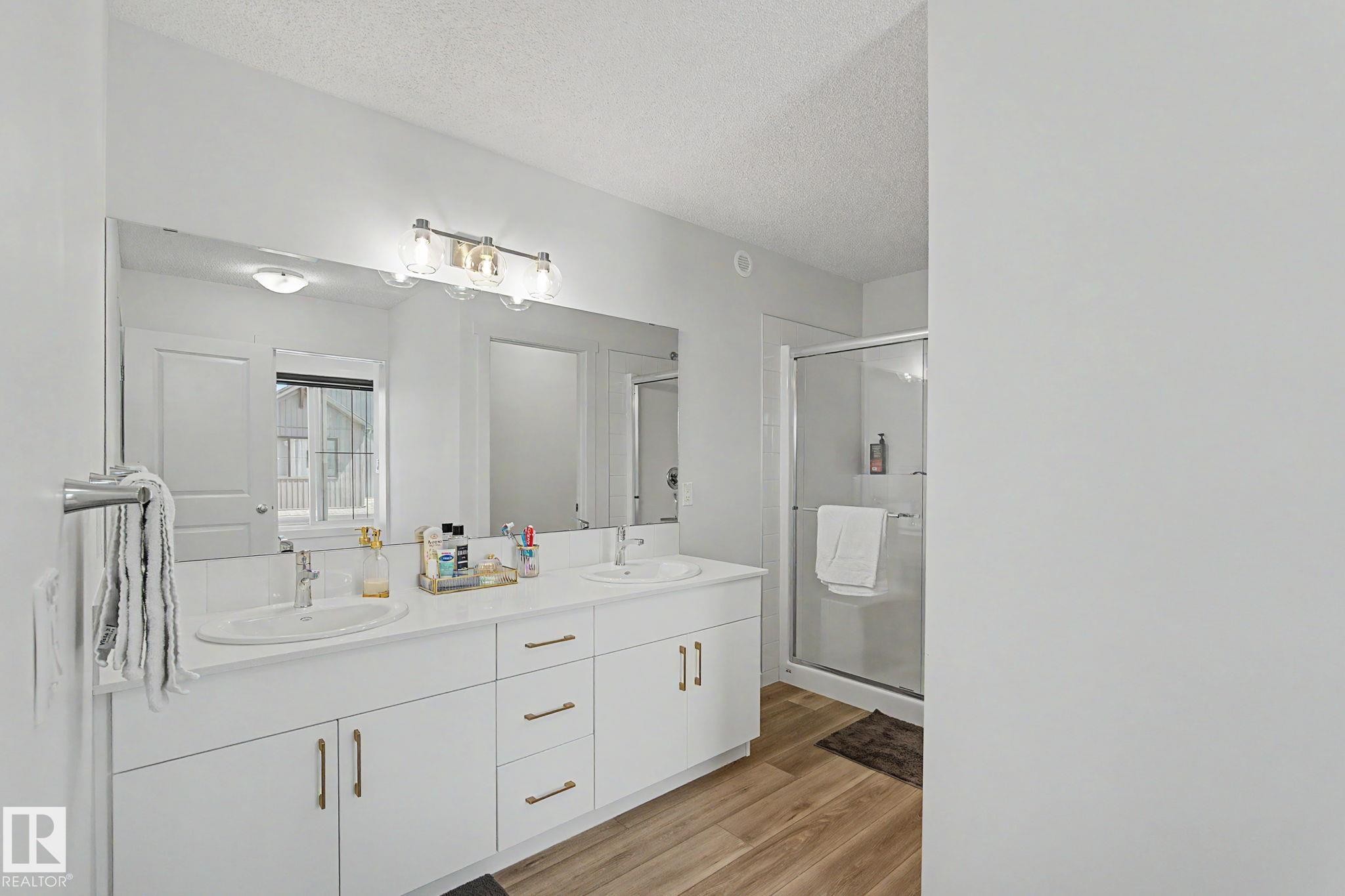 Bathroom featuring an extended double vanity with white cabinetry, gold-tone hardware, and an integrated mirror - #12 905 172 St Sw, Edmonton, AB - Indoor Photo Showing Bathroom