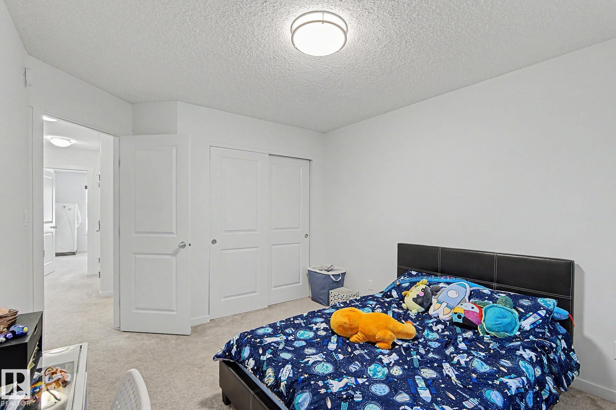 Neutral wall paint and textured ceiling with a flush-mount light fixture - #12 905 172 St Sw, Edmonton, AB - Indoor Photo Showing Bedroom