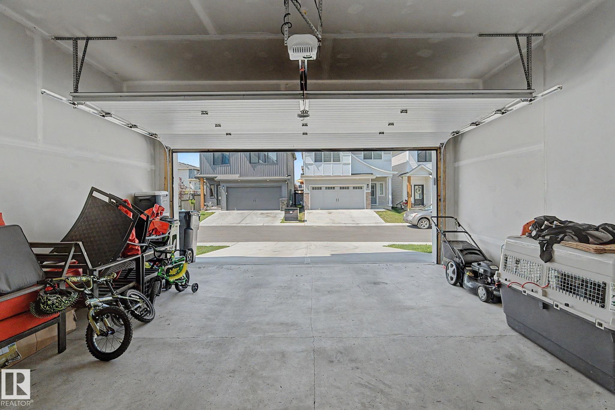 Spacious garage featuring a concrete floor, automatic garage door opener, and a panel-style overhead door - #12 905 172 St Sw, Edmonton, AB - Indoor Photo Showing Garage