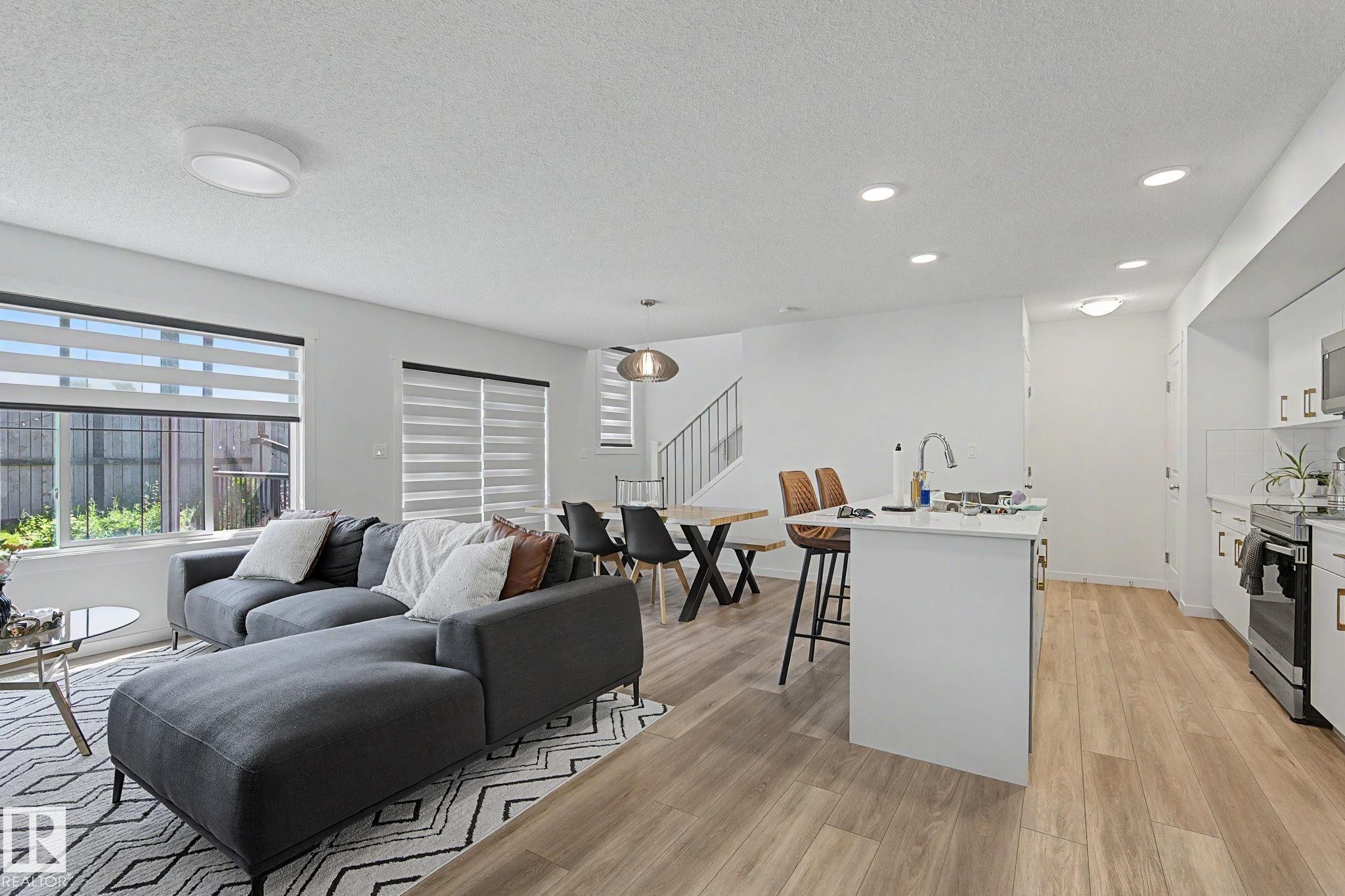 Open-concept living space featuring wood-finish flooring, recessed lighting, and white walls - #12 905 172 St Sw, Edmonton, AB - Indoor