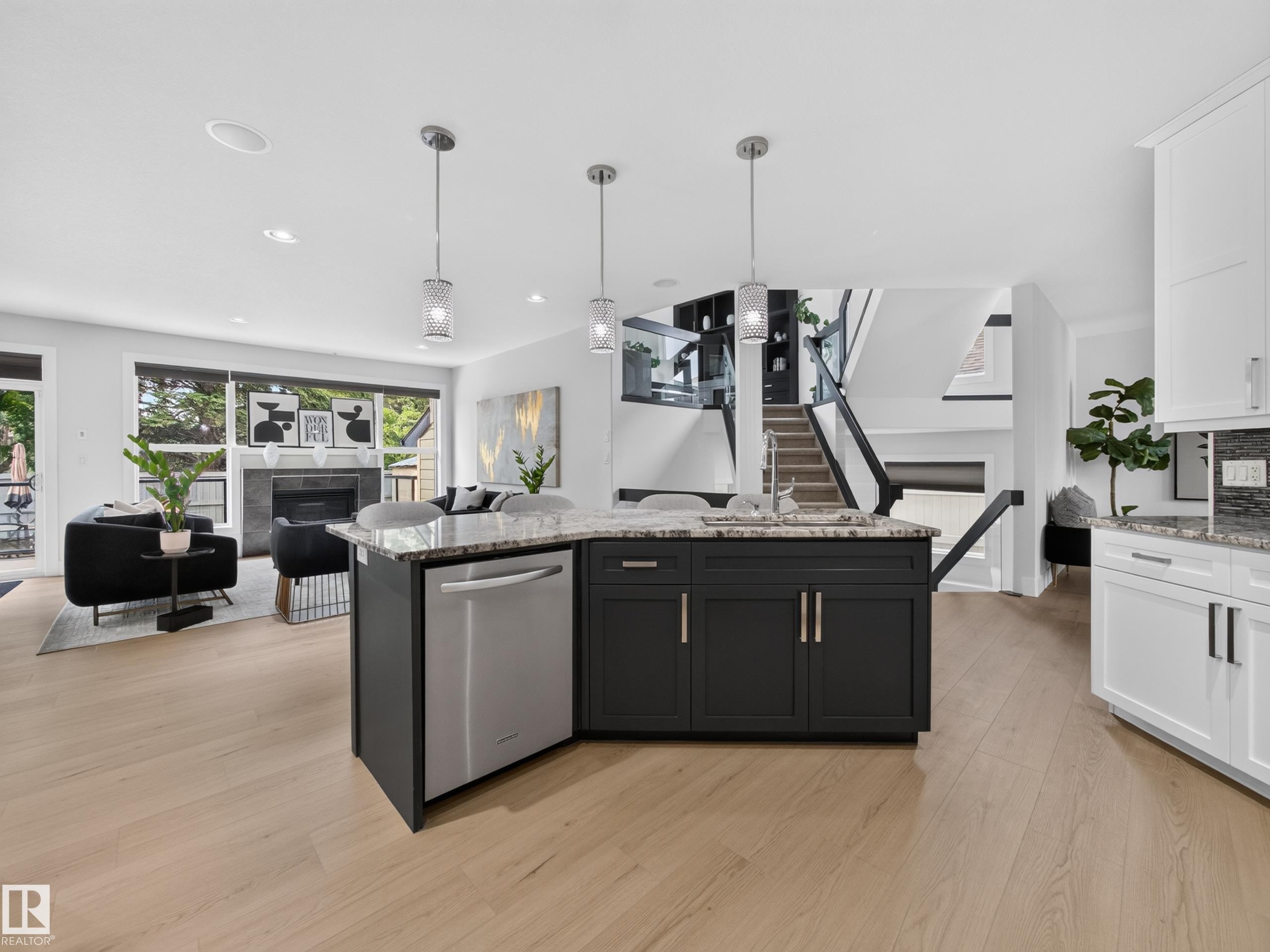 Central kitchen island with a granite countertop, undermount sink, and stainless steel dishwasher - #59 10550 Ellerslie Rd Sw, Edmonton, AB - Indoor Photo Showing Kitchen With Upgraded Kitchen
