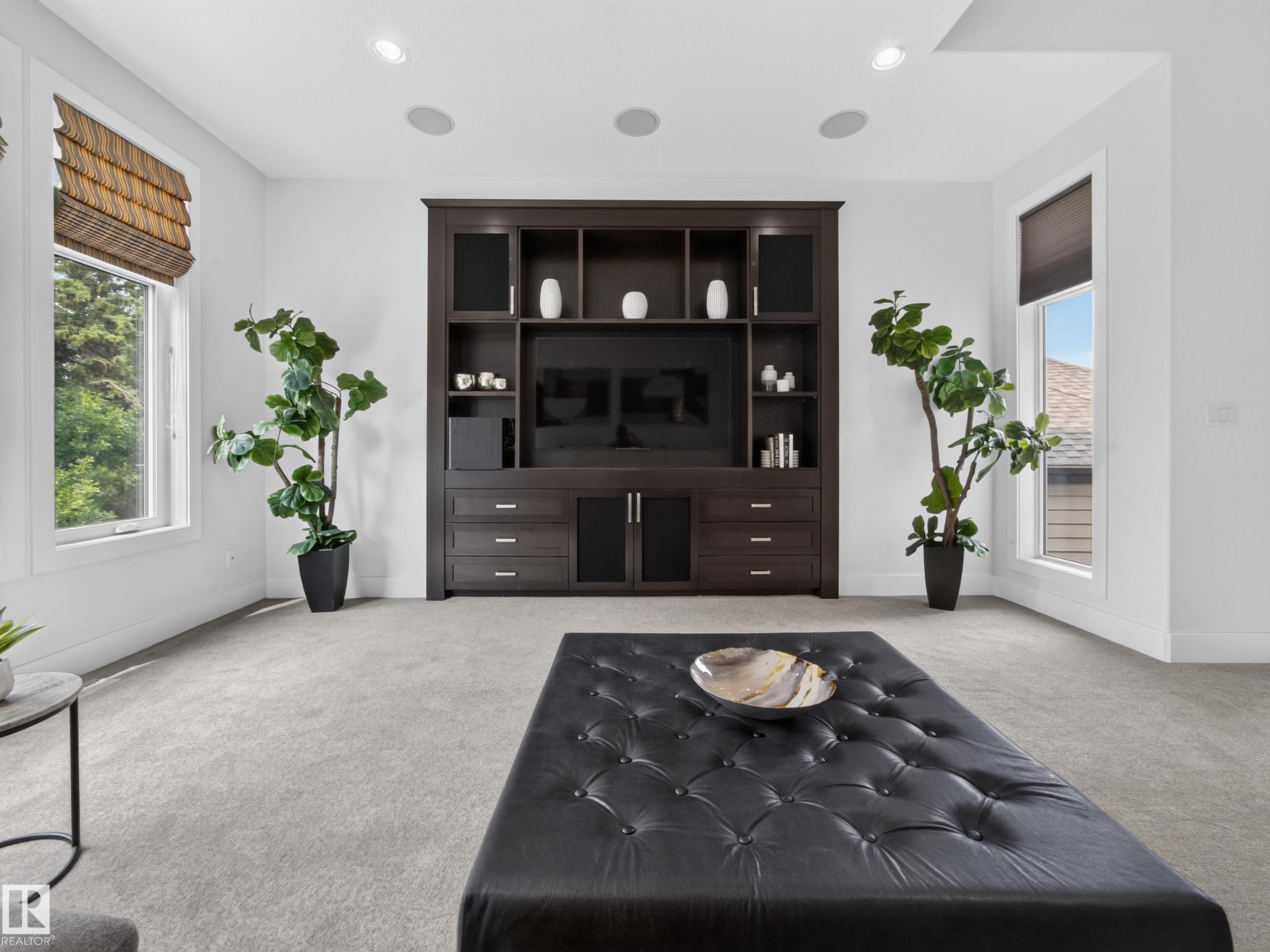 Built-in media center with ample storage, recessed ceiling lighting, two large windows with blinds, and light-toned carpeting - #59 10550 Ellerslie Rd Sw, Edmonton, AB - Indoor