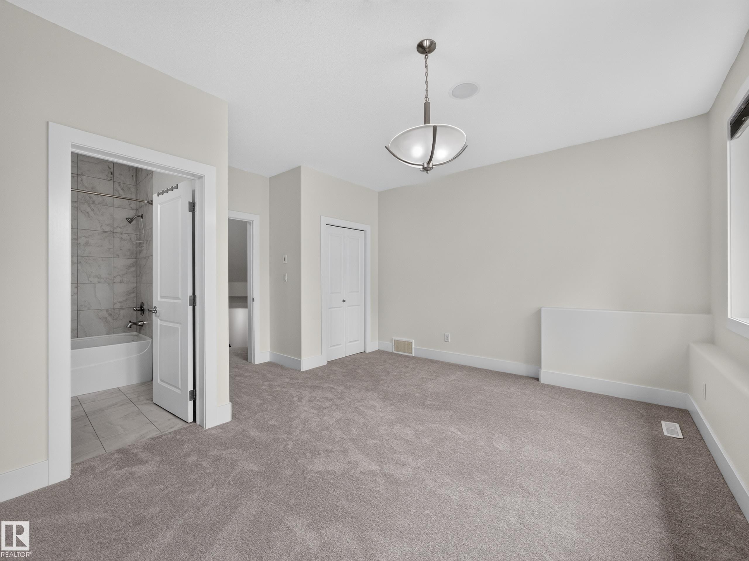 Spacious room featuring plush carpet, a built-in closet with bifold doors, and a contemporary ceiling light fixture - #59 10550 Ellerslie Rd Sw, Edmonton, AB - Indoor