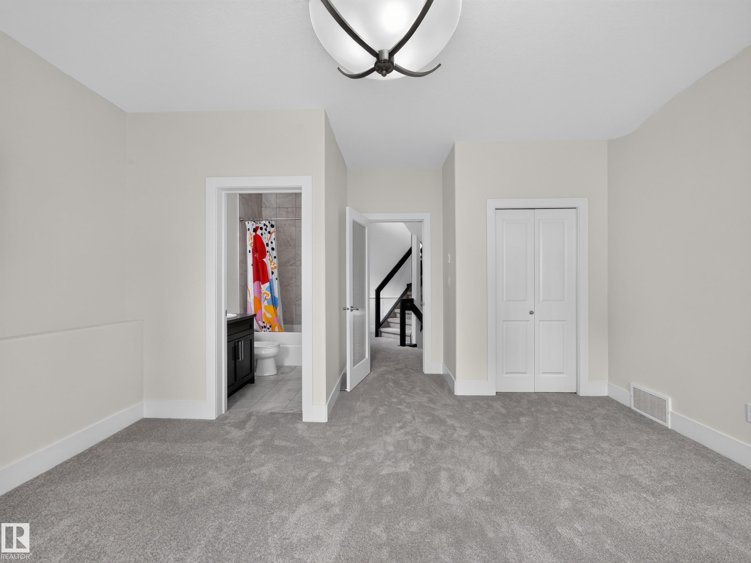 Carpeted upper-level space featuring a contemporary ceiling light fixture, white baseboards, and a bi-fold closet door - #59 10550 Ellerslie Rd Sw, Edmonton, AB - Indoor Photo Showing Other Room
