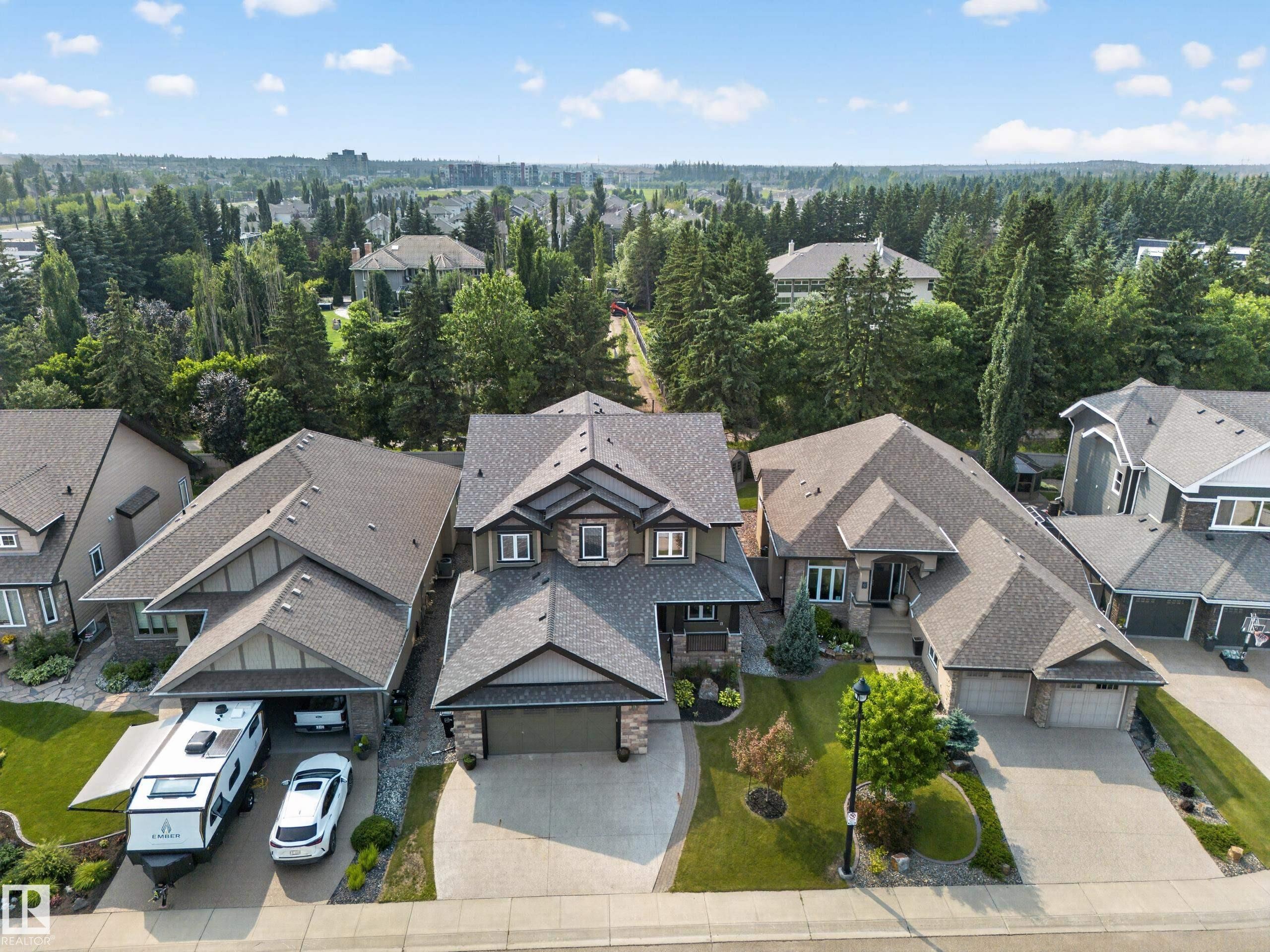 Property exterior featuring a stone and siding facade, multiple peaked rooflines, an attached two-car garage, and a concrete driveway - #59 10550 Ellerslie Rd Sw, Edmonton, AB - Outdoor With Facade