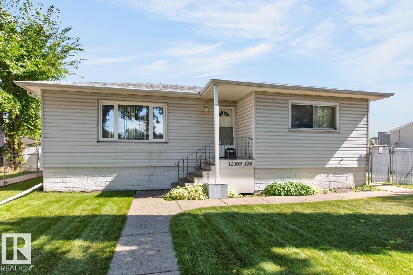 Light-colored siding exterior with a concrete walkway leading to the front entry - 12309 128 Street Nw, Edmonton, AB