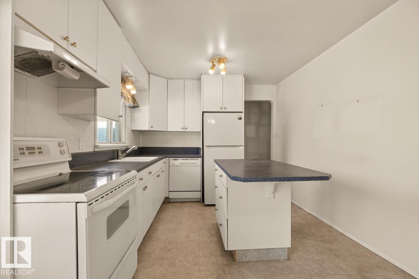 White cabinetry, dark countertops, white appliance package, vinyl flooring, and a kitchen island - 12309 128 Street Nw, Edmonton, AB