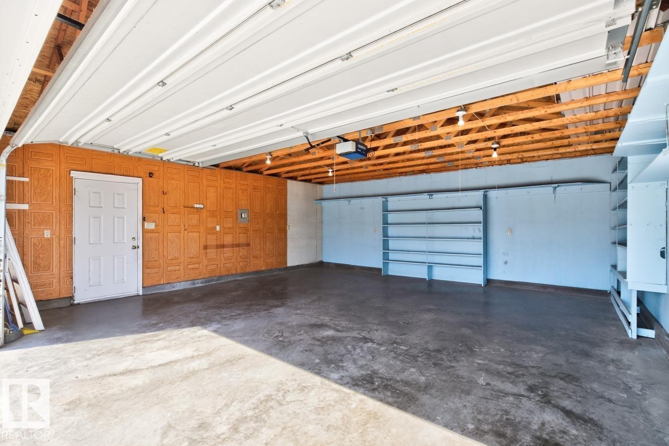 Concrete flooring, exposed wood beam ceiling, built-in shelving, white overhead garage door, built-in storage cabinets - 12309 128 Street Nw, Edmonton, AB