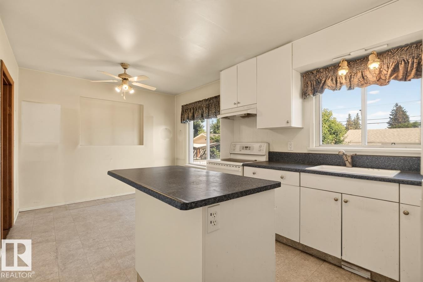 Kitchen featuring white cabinetry, dark countertops, a built-in sink, and a ceiling fan with integrated lighting - 12309 128 Street Nw, Edmonton, AB